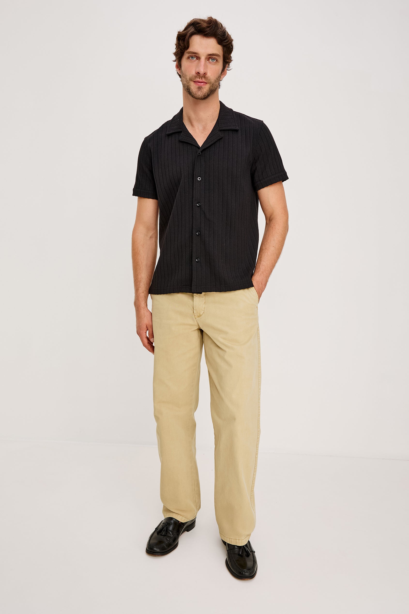 Corrin is a short sleeve camp style shirt with a notched lapel in Black colorway. Full body front view featured on model.