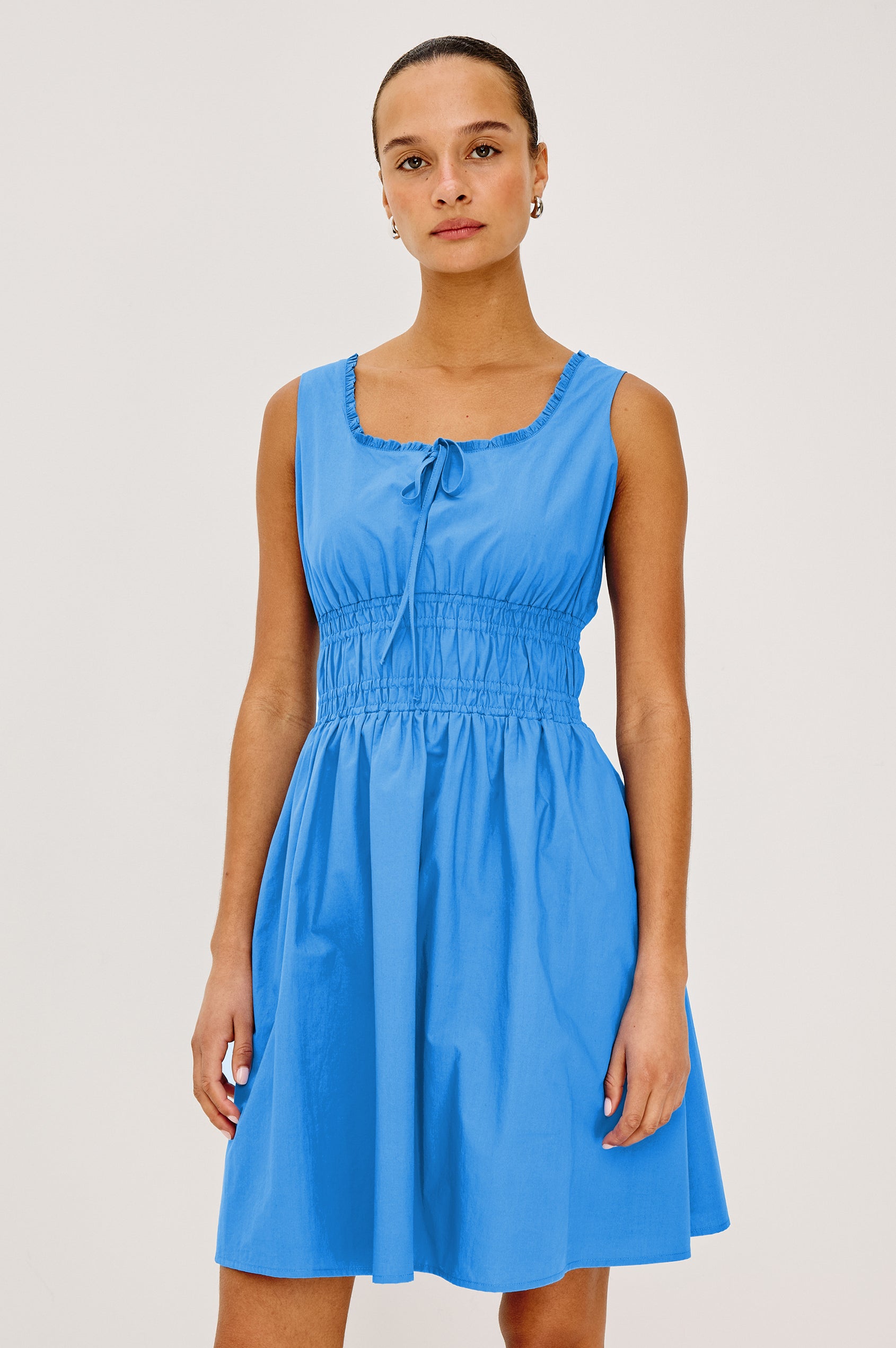 Cosette Mini Dress in Cotton Poplin With Square Neckline, Center Bust Ties, Ruffle Trim, and Smocked Waist in Harbor Blue Colorway - Upper Body View Featured on Model