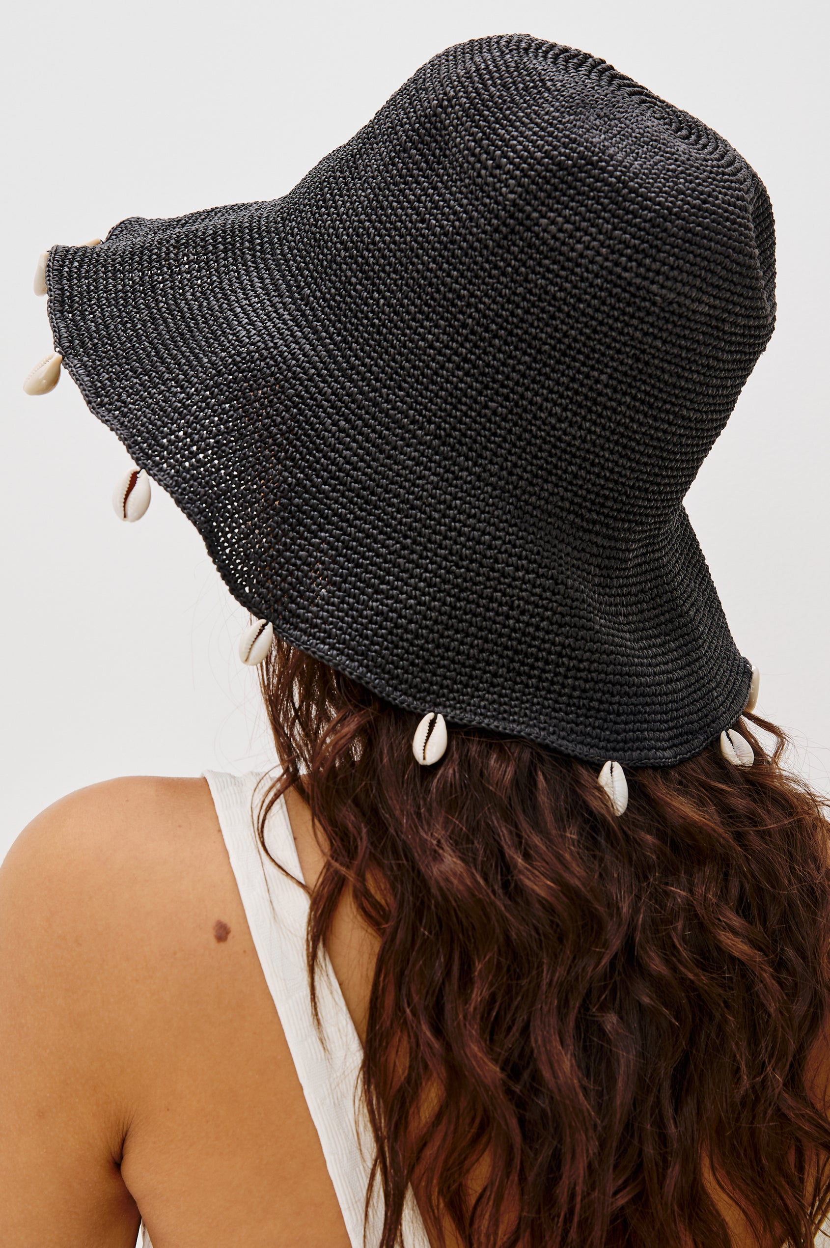 Crete Rattan Wide Brim Hat with Hanging Sea Shells at Edge in Black Colorway. Back Detailed View Shown on Model.