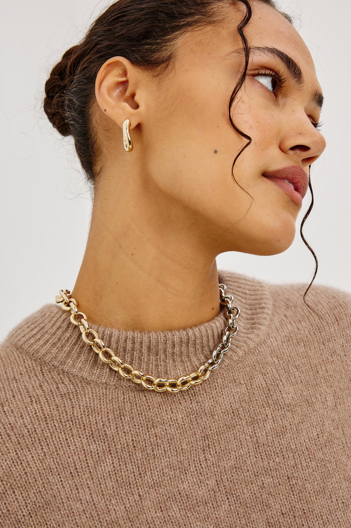 Curved Hoop Earrings With Hinged-Back Closure, Sculptural Shape, and Interior Rails Embossed Logo in Gold Colorway - Side View Featured on Model