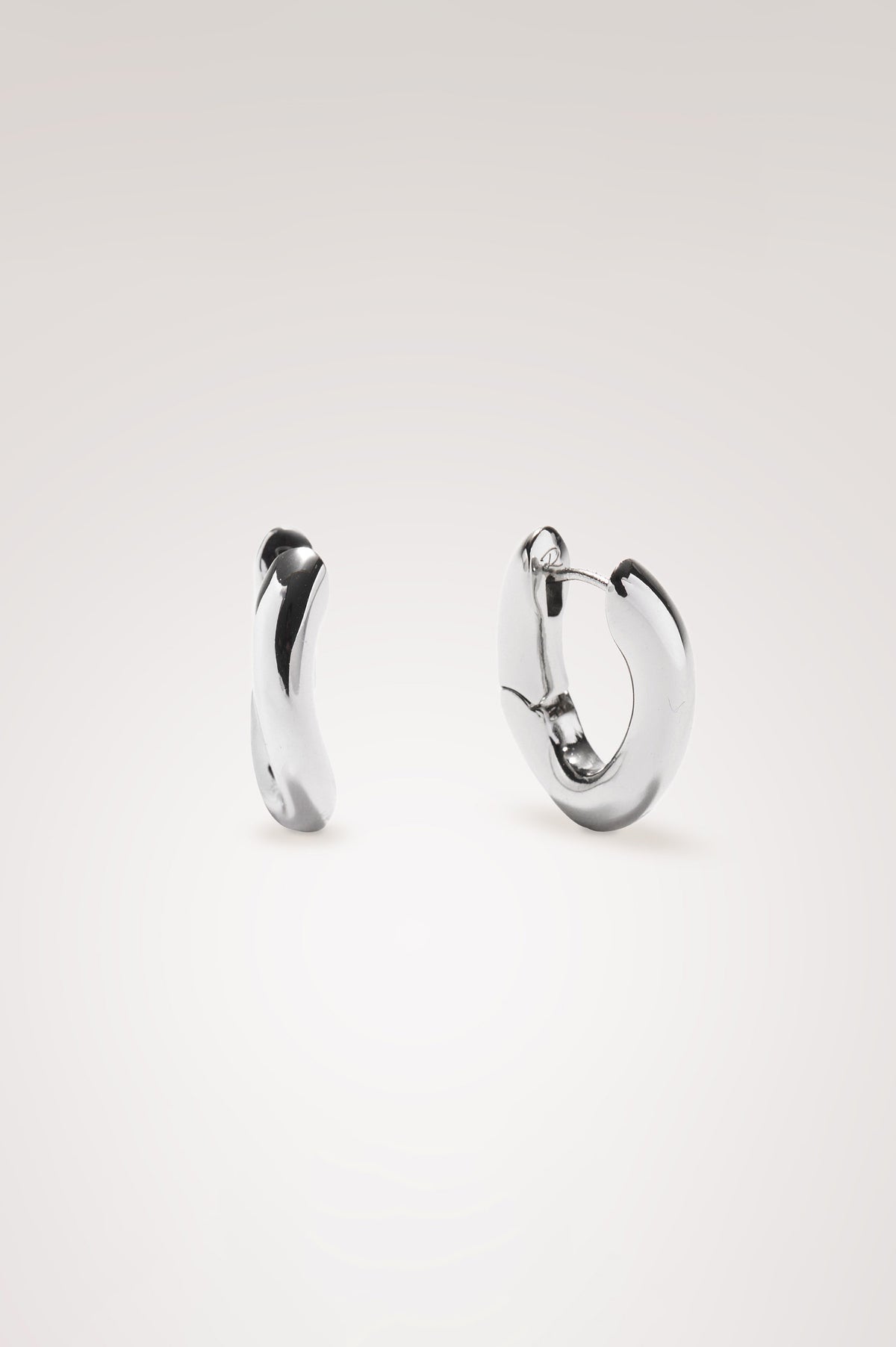 Curved Hoop Earrings With Hinged-Back Closure, Sculptural Shape, and Interior Rails Embossed Logo in Silver Colorway - Flat Lay Product View Featured