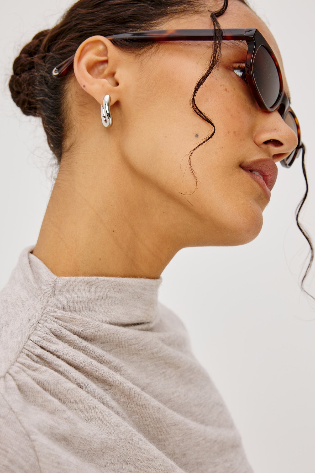 Curved Hoop Earrings With Hinged-Back Closure, Sculptural Shape, and Interior Rails Embossed Logo in Silver Colorway - Side View Featured on Model