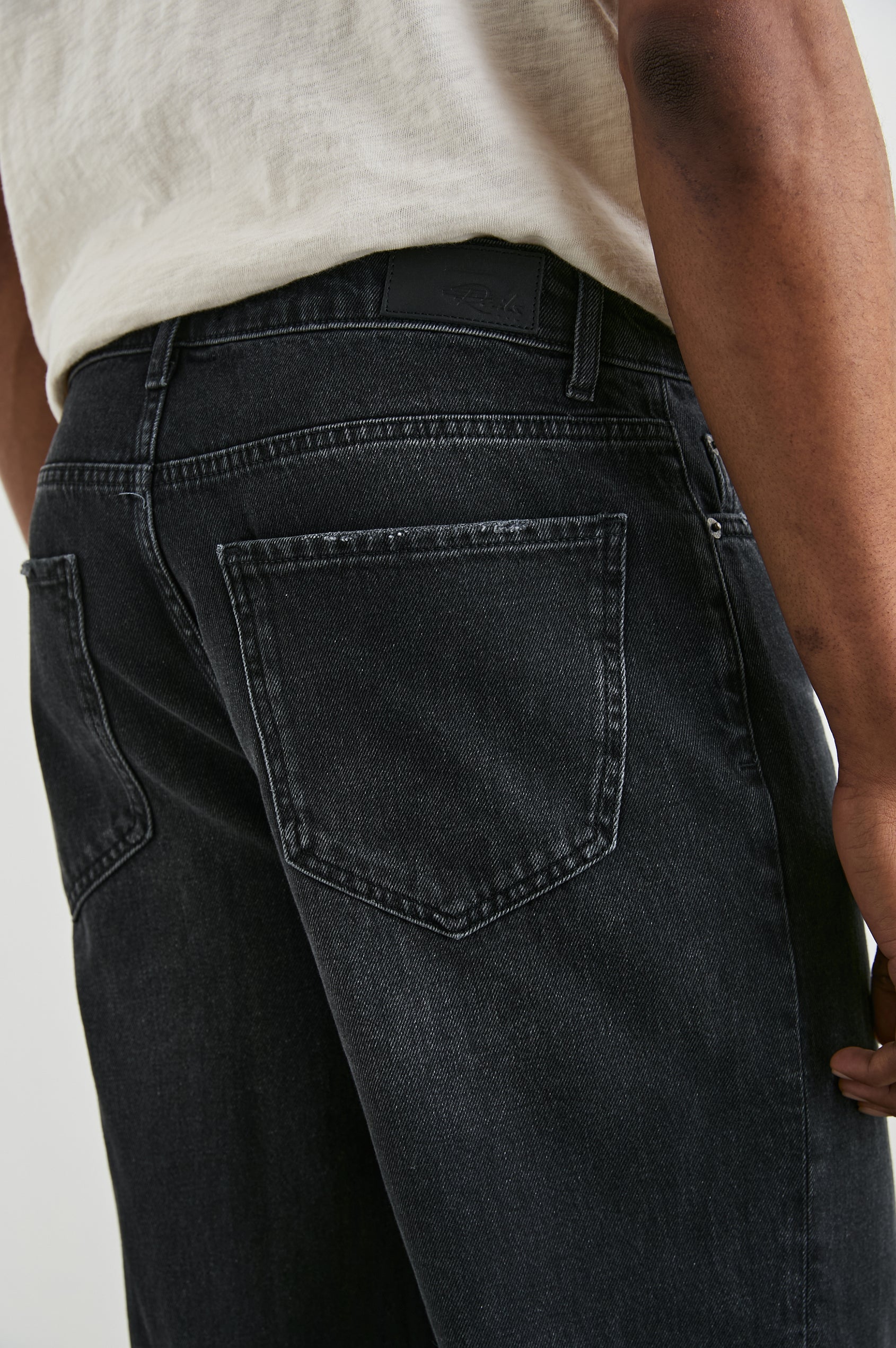 Cutler 90's Loose Jeans with Belt Loops, Two Front Pockets plus a Coin Pocket and Two Back Patch Pockets in Distressed Black Colorway - Back View Featured on Model