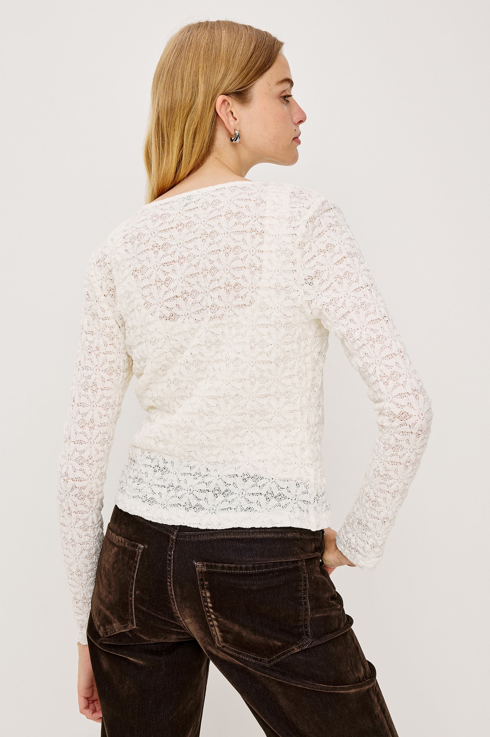 Cyrah is a long sleeve button front lace cardigan in Ivory colorway. Back view with top buttoned featured on model.