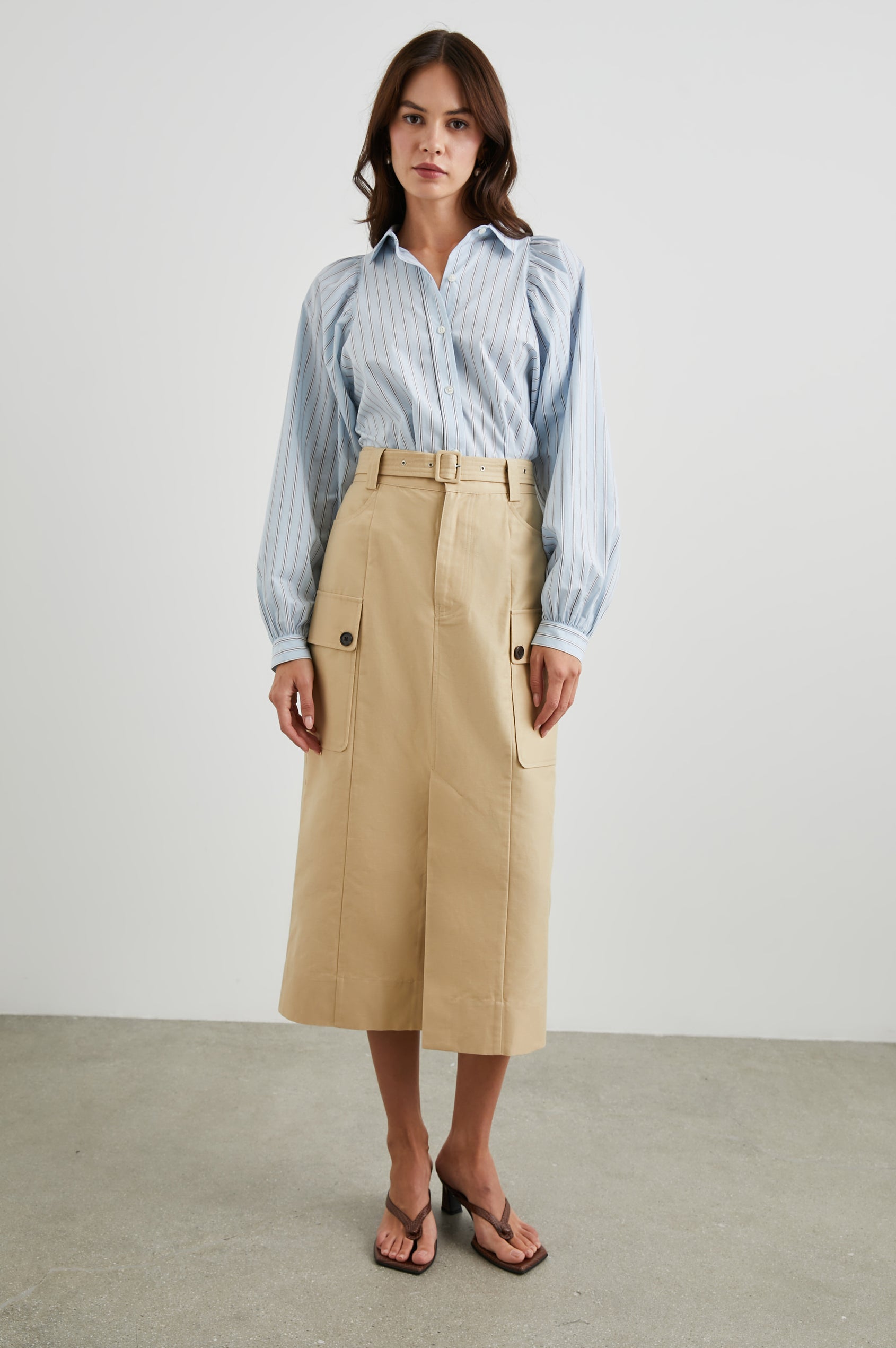 Cyrus Midi Skirt with a Center Slit, Belt Loops, a Fabric Belt, Two Front Pockets and Two Side Button Flap Pockets in Khaki Colorway, with Dark Buttons - Front Full Body View Featured on Model 