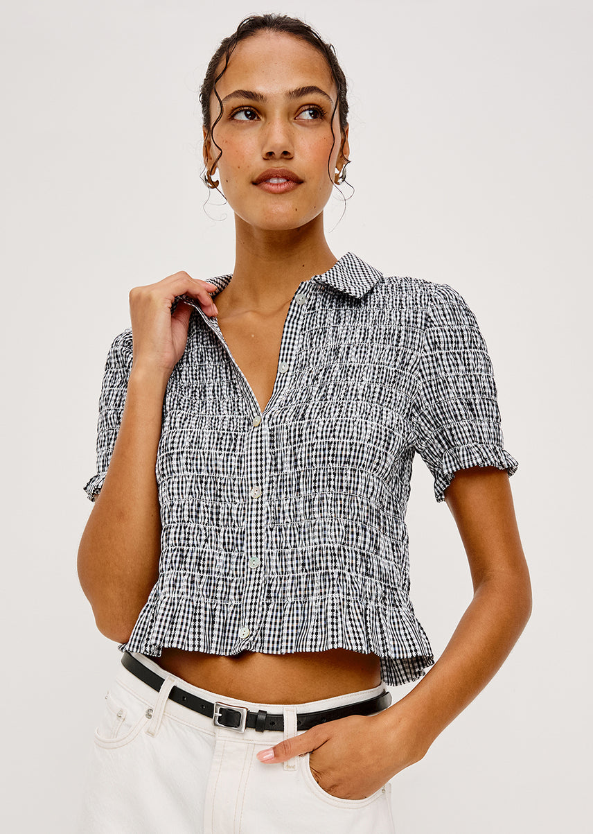 Woman wearing a black and white gingham top against a white background