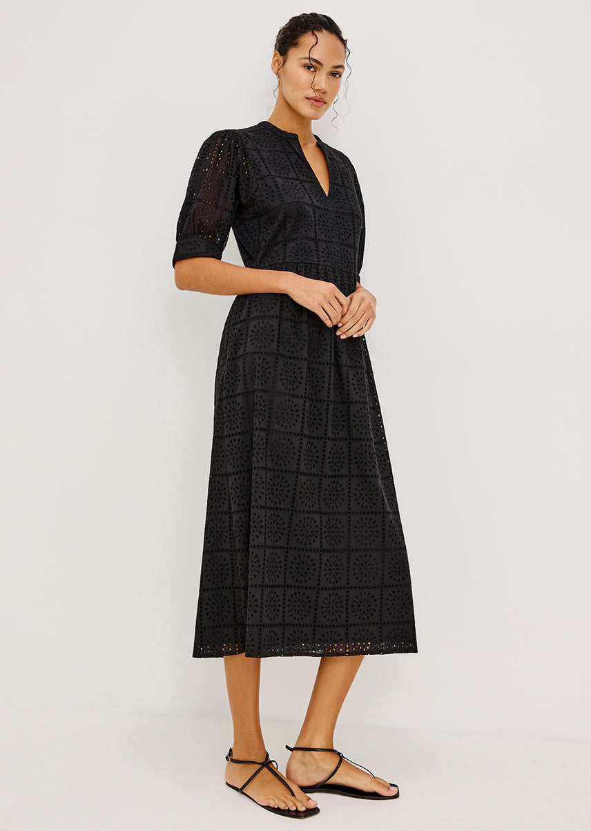 Woman wearing a black eyelet maxi dress against a white background