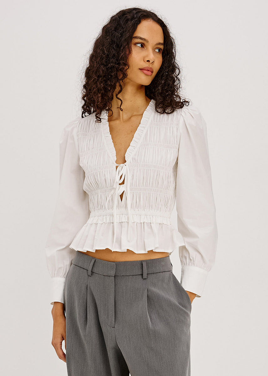 Woman wearing a white long sleeve top with grey pants