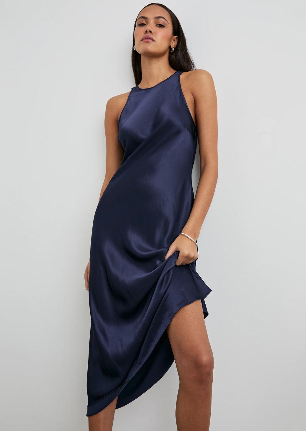 Woman wearing a navy blue satin dress against a white background