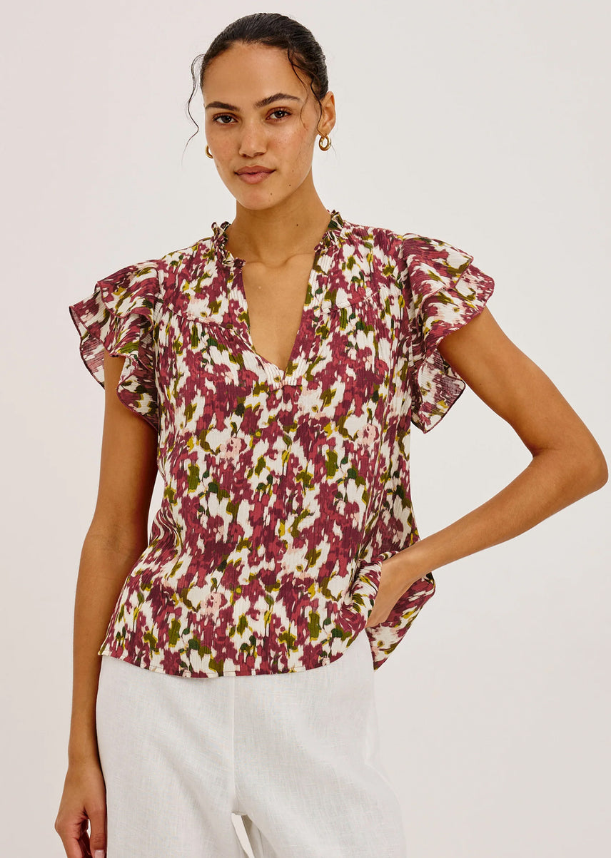 Woman wearing a floral blouse with ruffled sleeves on a plain background
