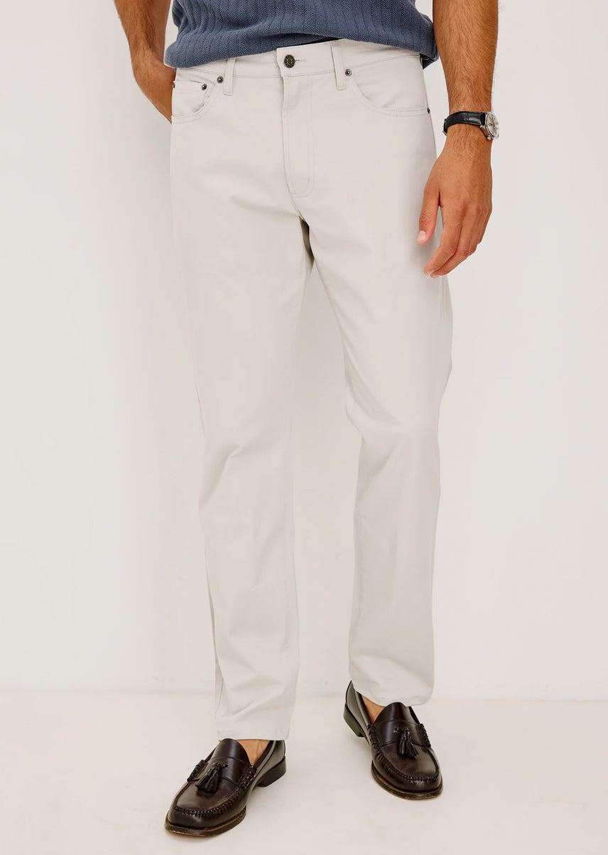 Person wearing light gray jeans and dark shoes on a white background