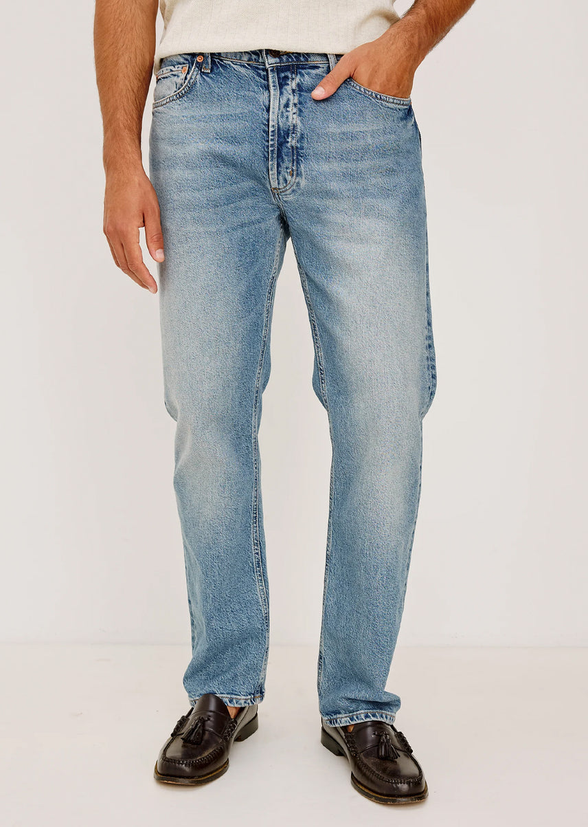 Person wearing light blue jeans on a plain background