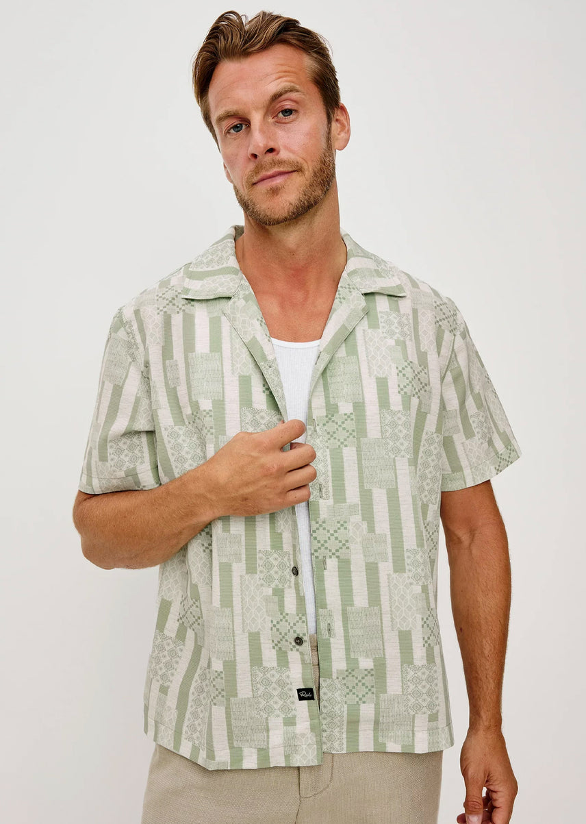 Man wearing a green patterned shirt against a white background
