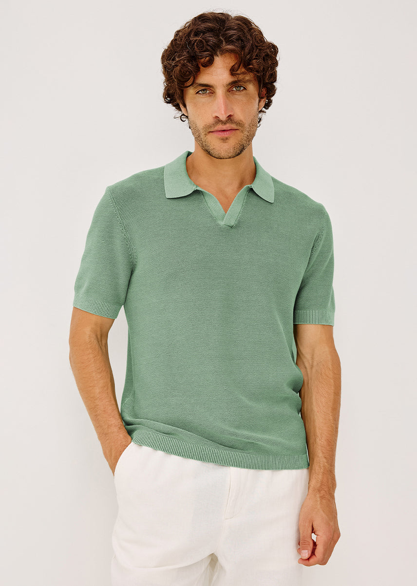 Man dressed in a green shirt wearing white pants