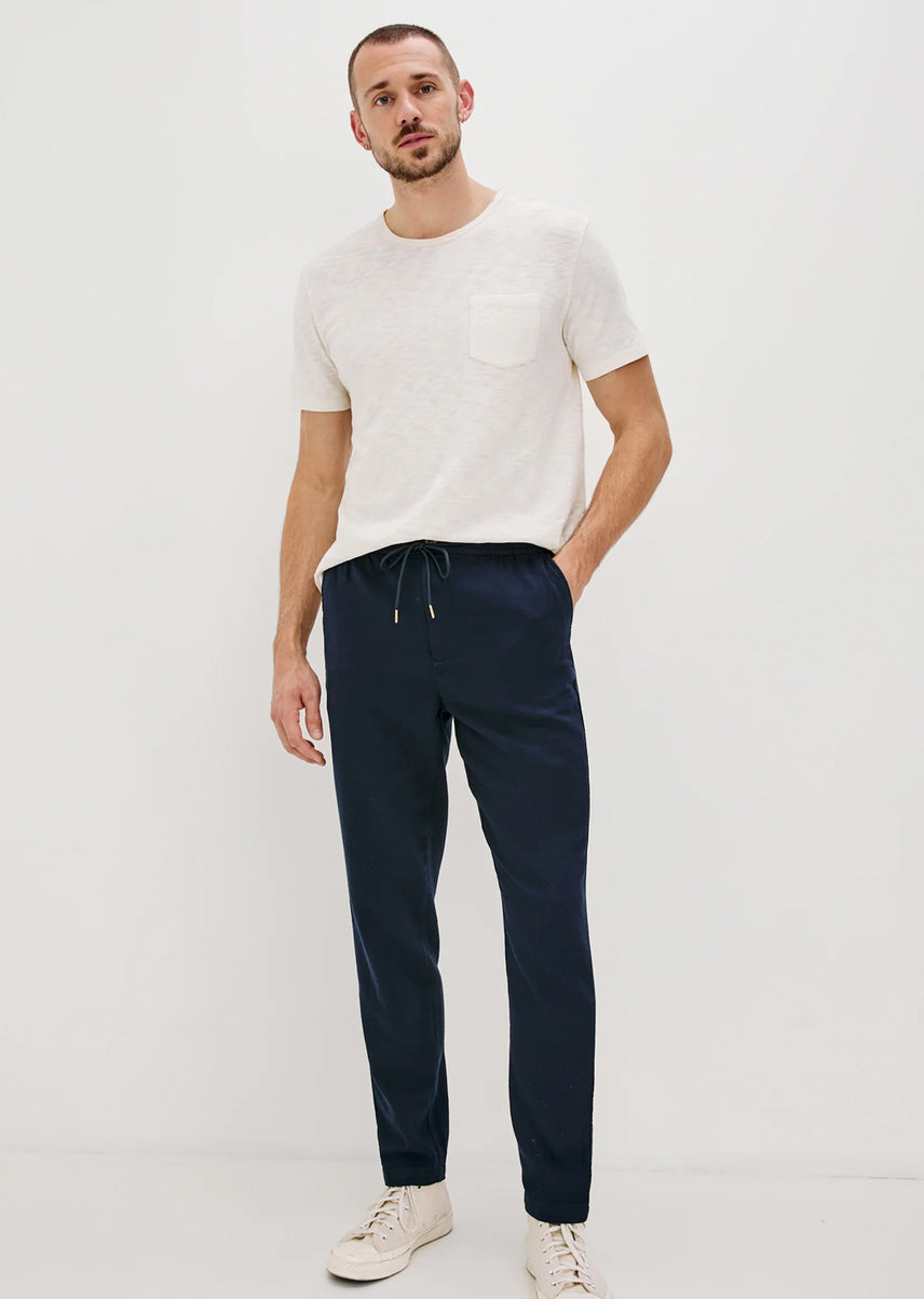 Man wearing a white t-shirt and navy pants on a white background
