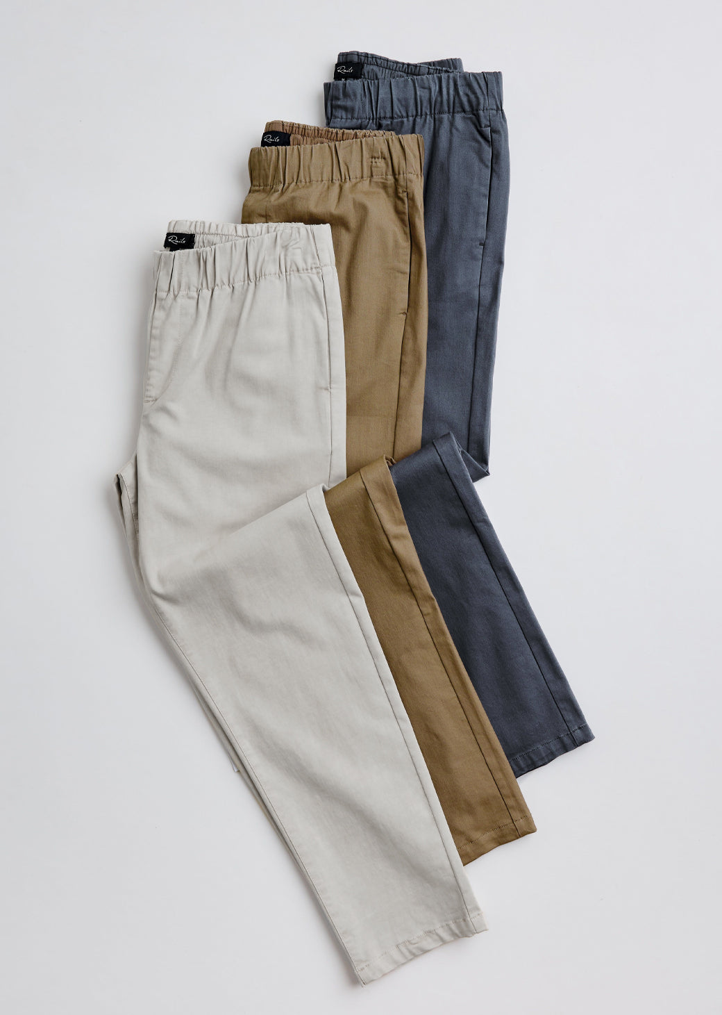 Three pairs of pants in beige, brown, and blue on a white background