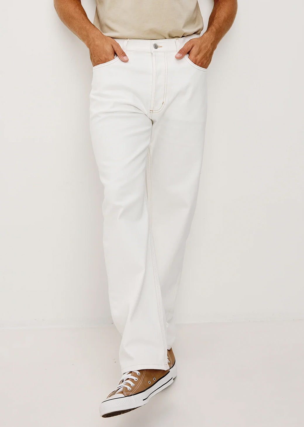 Man wearing white pants and a beige shirt on a white background