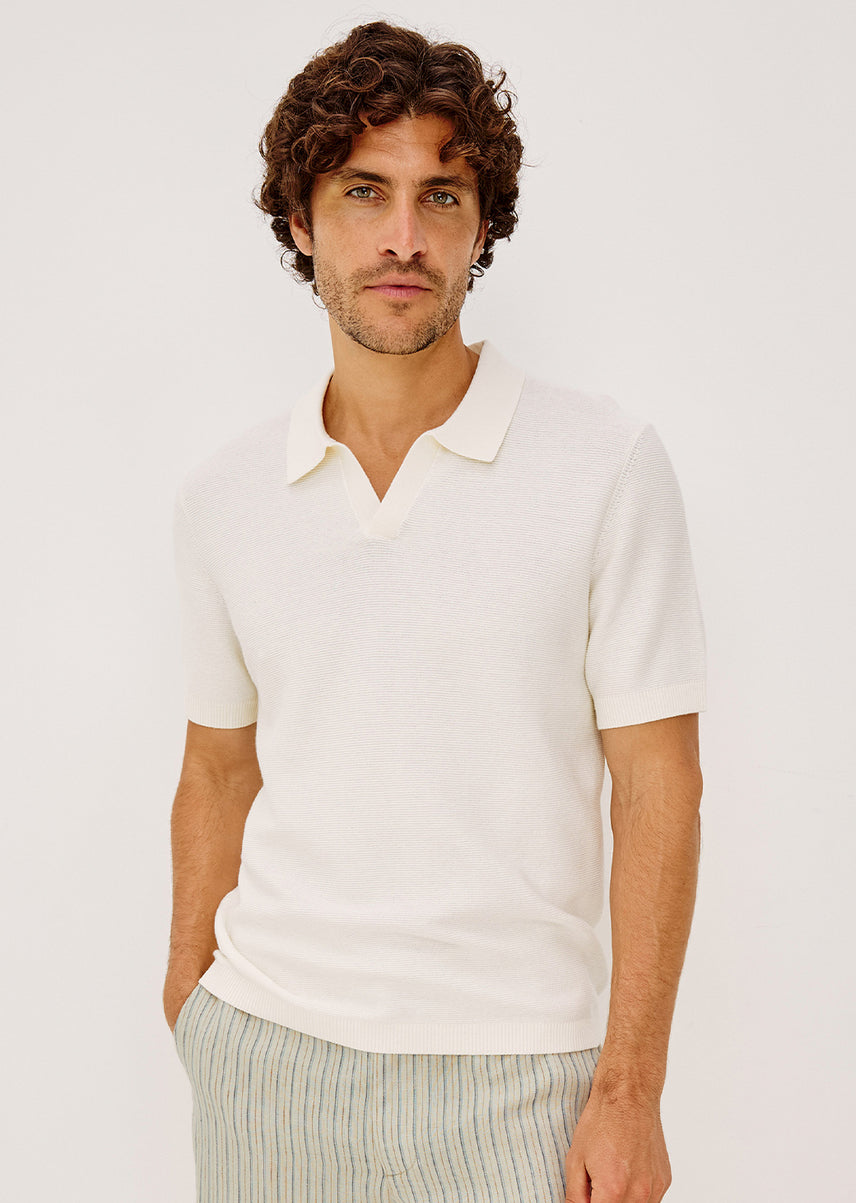 Man wearing an ivory polo against a white background