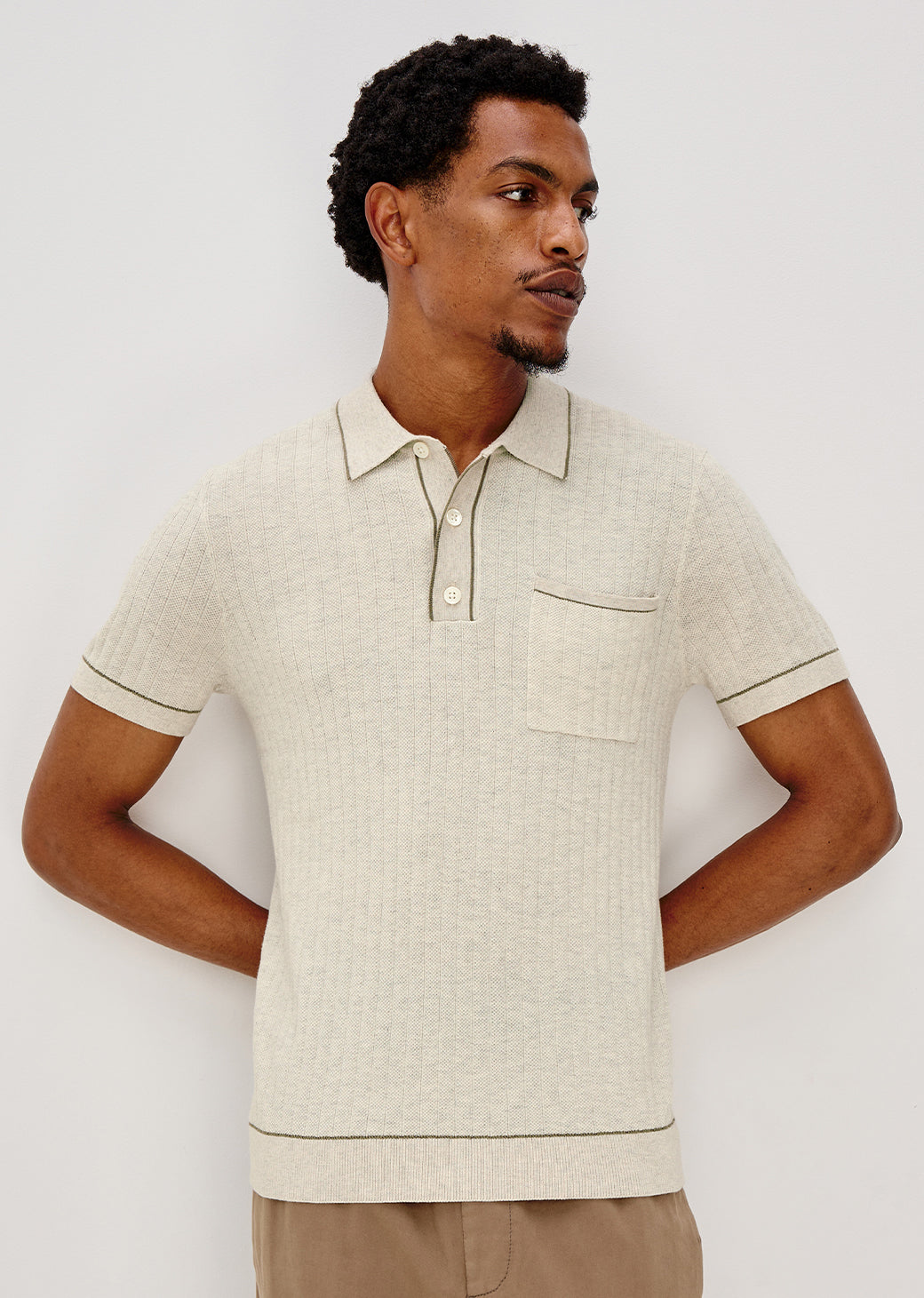 Man wearing a beige polo shirt against a white background.