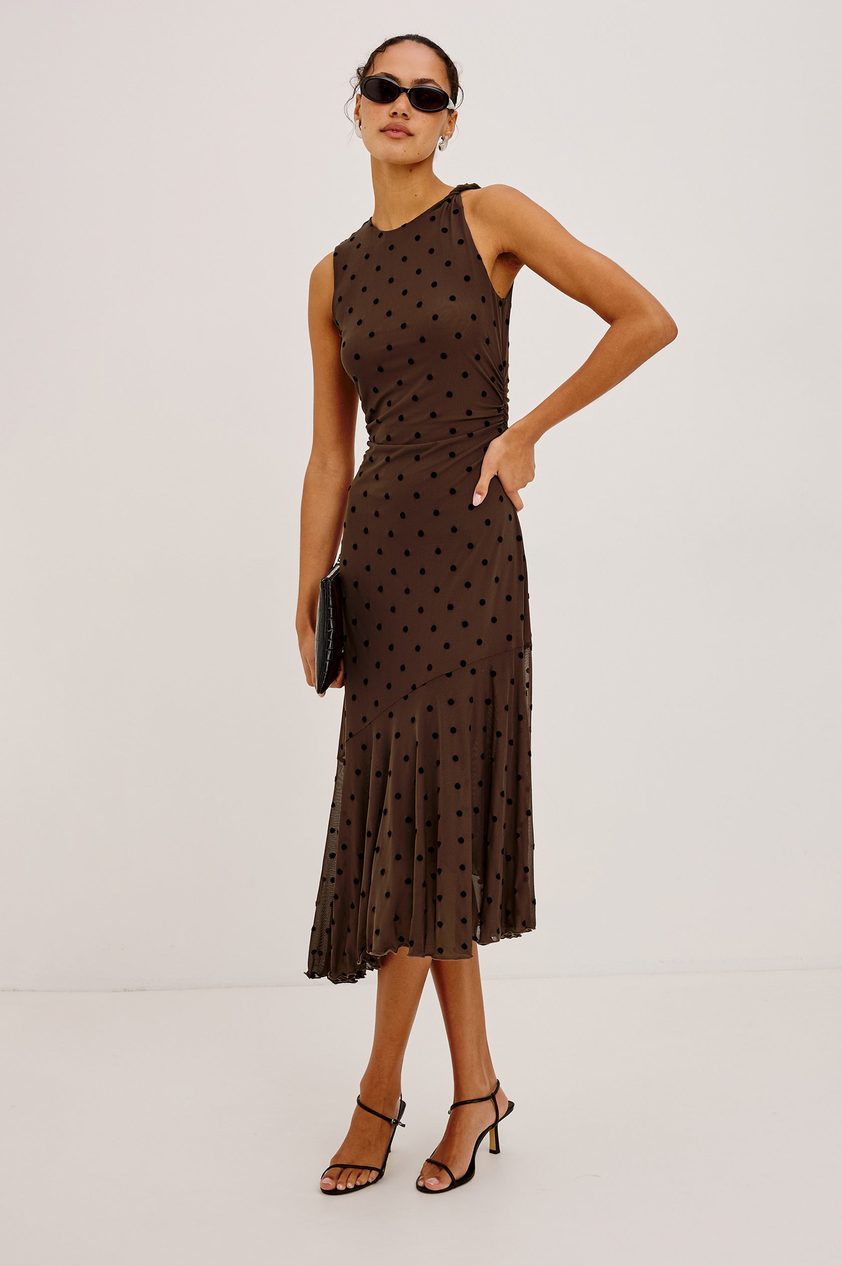 Daija Midi Dress in Self-Lined Mesh With High Neckline, Fitted Bodice, Side Waist Ruching, Bias Cut Skirt, and Asymmetric Hem in Chocolate Polka Dot Colorway - Full Body Front View Featured on Model
