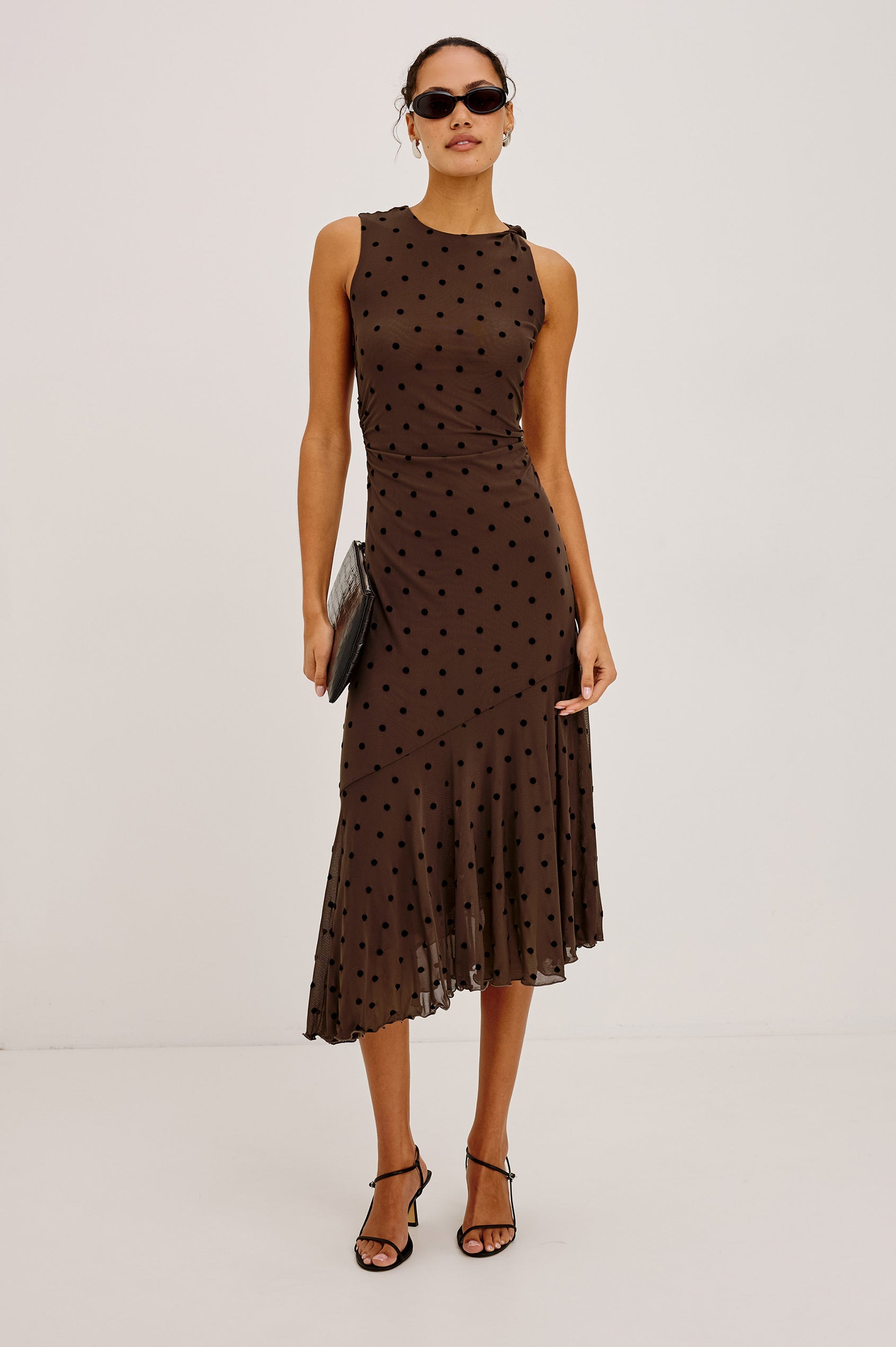 Daija Midi Dress in Self-Lined Mesh With High Neckline, Fitted Bodice, Side Waist Ruching, Bias Cut Skirt, and Asymmetric Hem in Chocolate Polka Dot Colorway - Full Body Front View Featured on Model