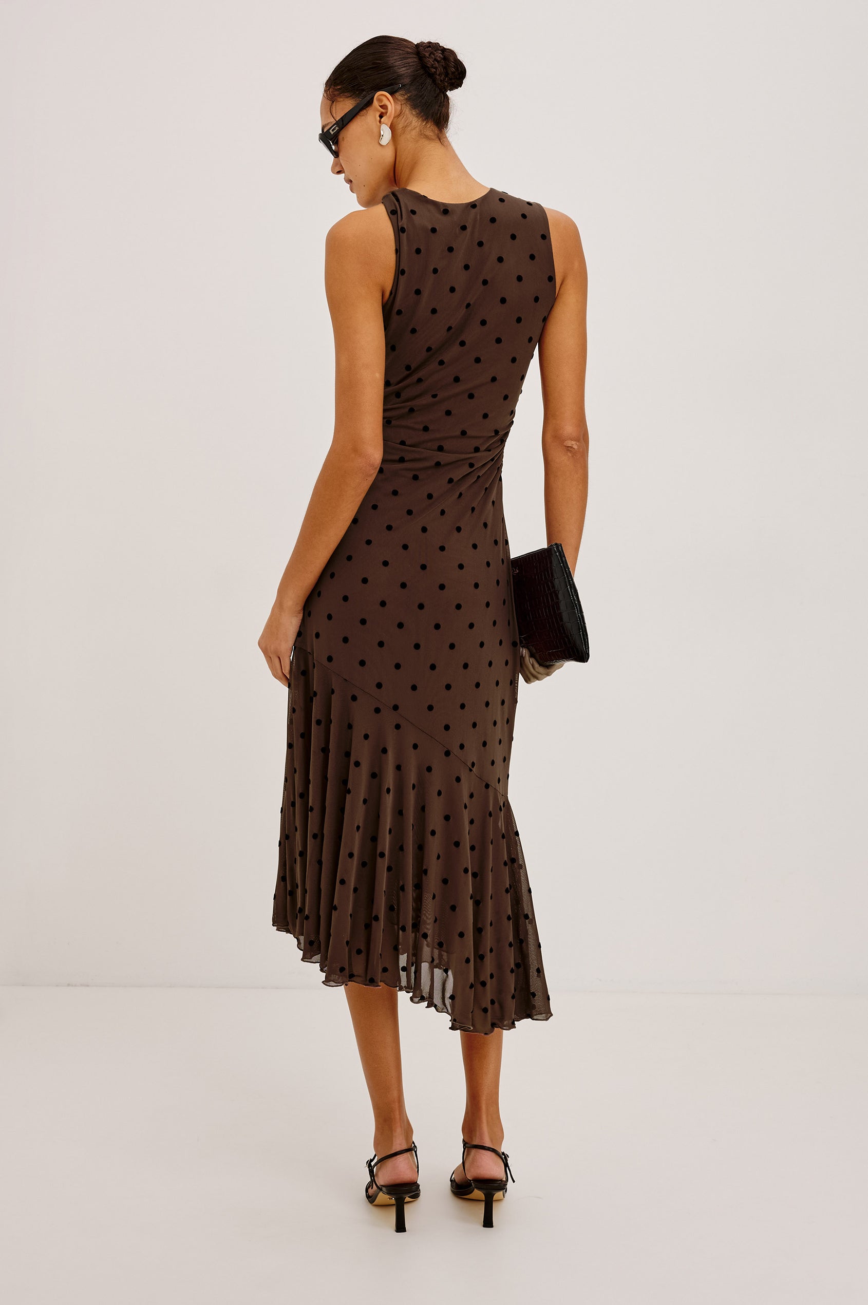 Daija Midi Dress in Self-Lined Mesh With High Neckline, Fitted Bodice, Side Waist Ruching, Bias Cut Skirt, and Asymmetric Hem in Chocolate Polka Dot Colorway - Full Body Back View Featured on Model