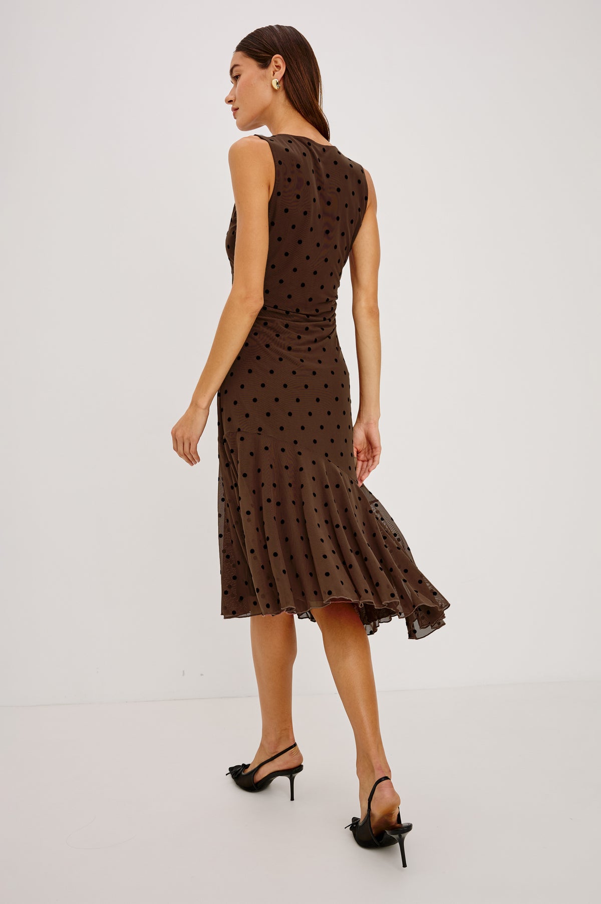 Daija Midi Dress in Self-Lined Mesh With High Neckline, Fitted Bodice, Side Waist Ruching, Bias Cut Skirt, and Asymmetric Hem in Chocolate Polka Dot Colorway - Full Body Back View Featured on Model