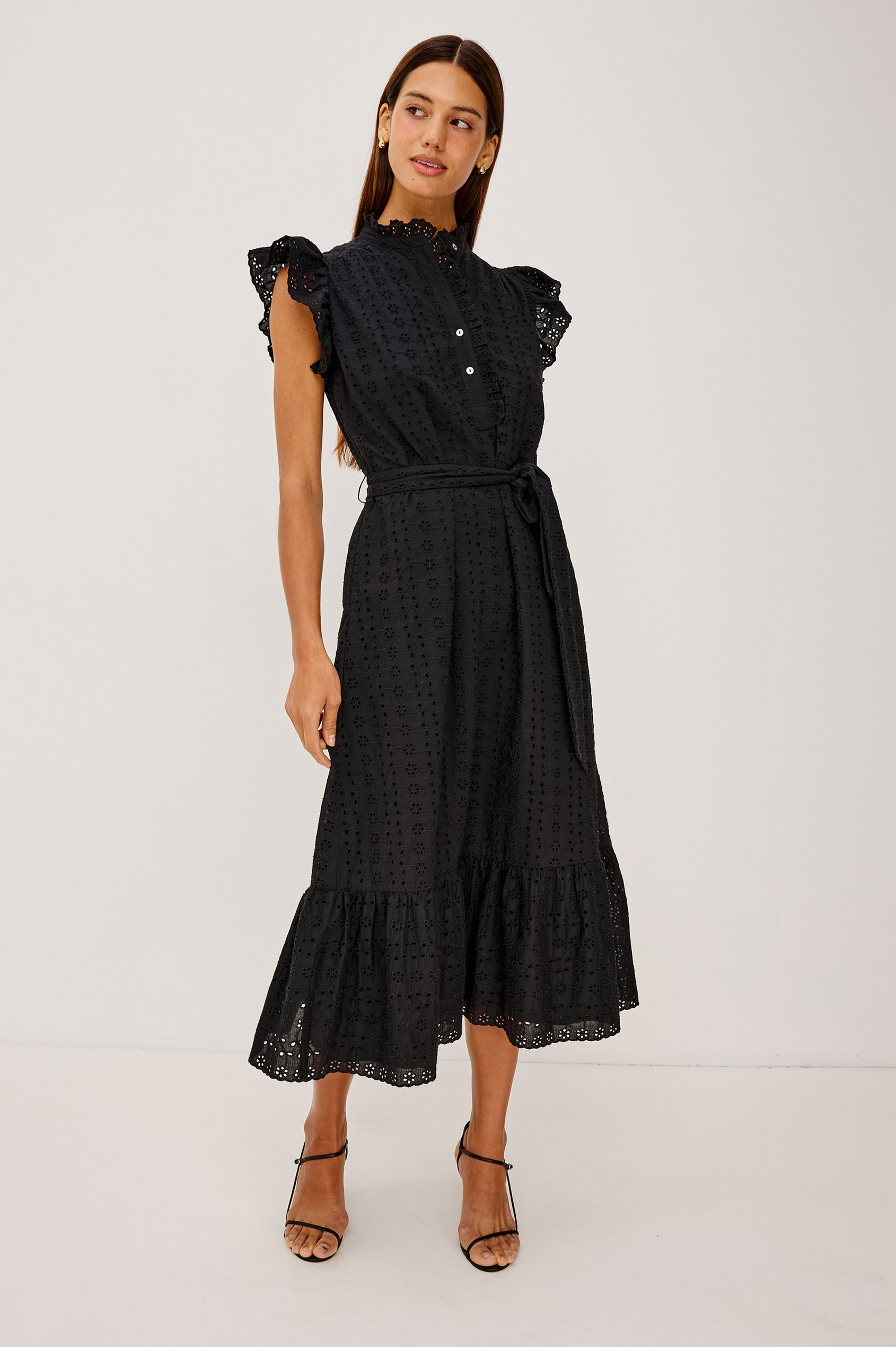 Darcy Midi Dress in Cotton Voile With Ruffled Collarless Neckline, Half-Placket, Eyelet Cutwork, Short Flutter Sleeves, Wide Self-Tie Belt, and Lined Skirt in Black Eyelet Colorway - Full Body Front View Featured on Model