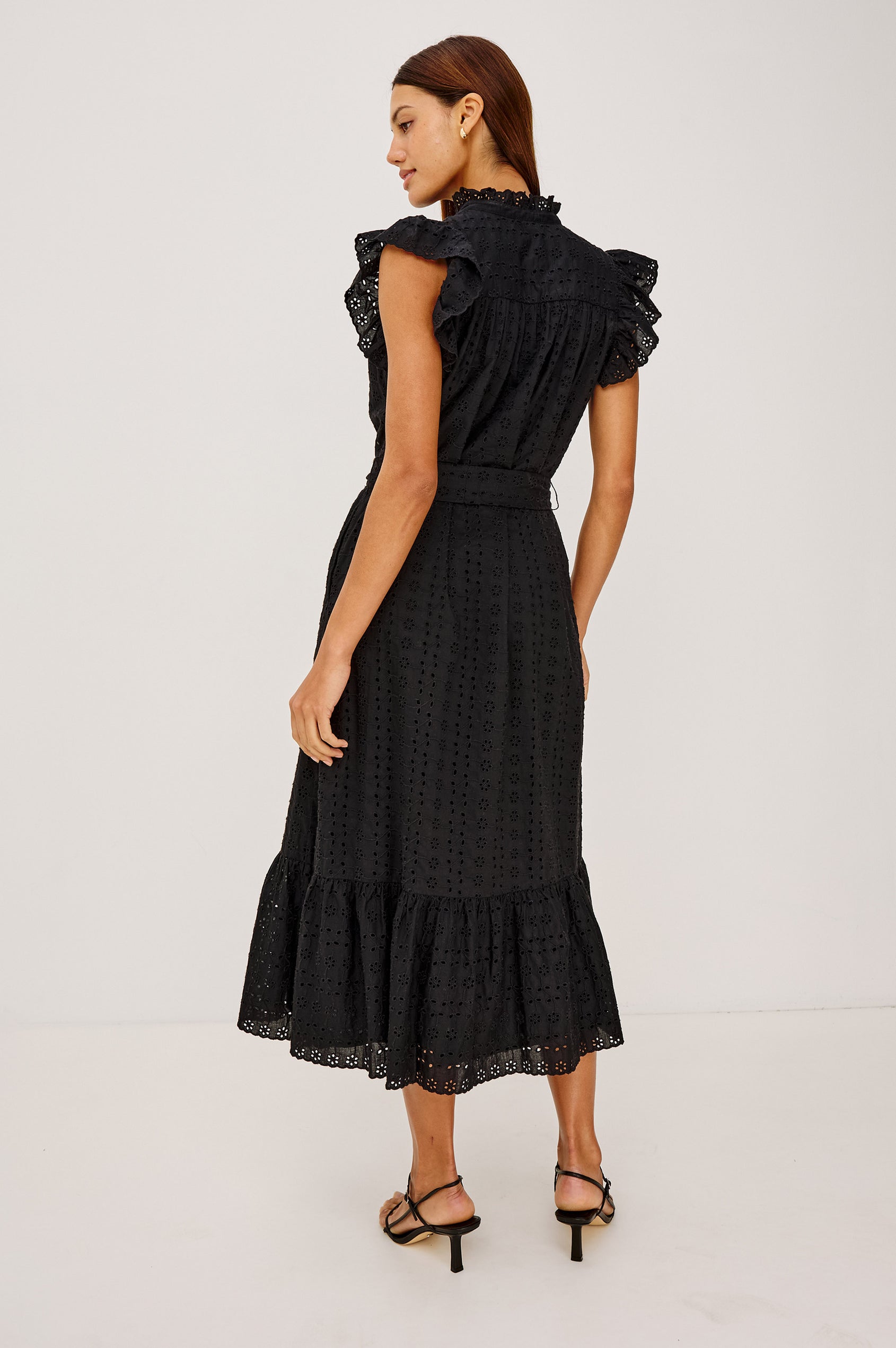 Darcy Midi Dress in Cotton Voile With Ruffled Collarless Neckline, Half-Placket, Eyelet Cutwork, Short Flutter Sleeves, Wide Self-Tie Belt, and Lined Skirt in Black Eyelet Colorway - Full Body Back View Featured on Model