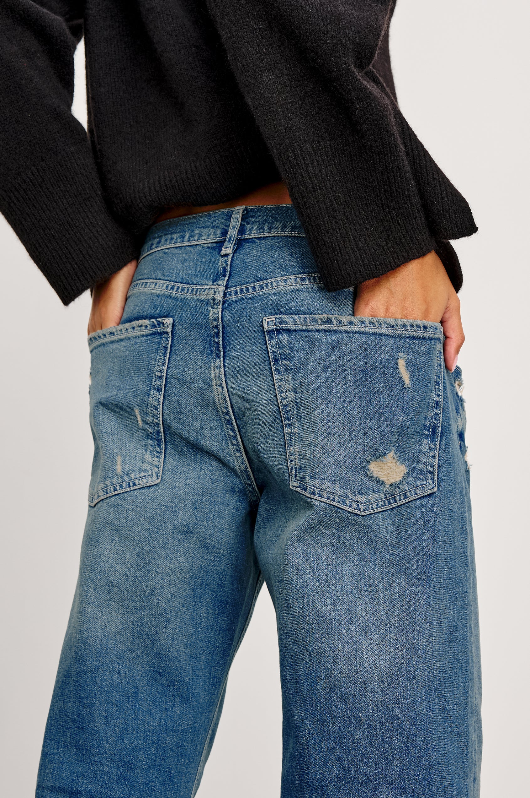 Del Mar low slung baggy boyfriend 5-pocket jean in medium wash Tinted Indigo Destroy, with light destruction near front pockets - back detail view hands in back pockets featured on model.