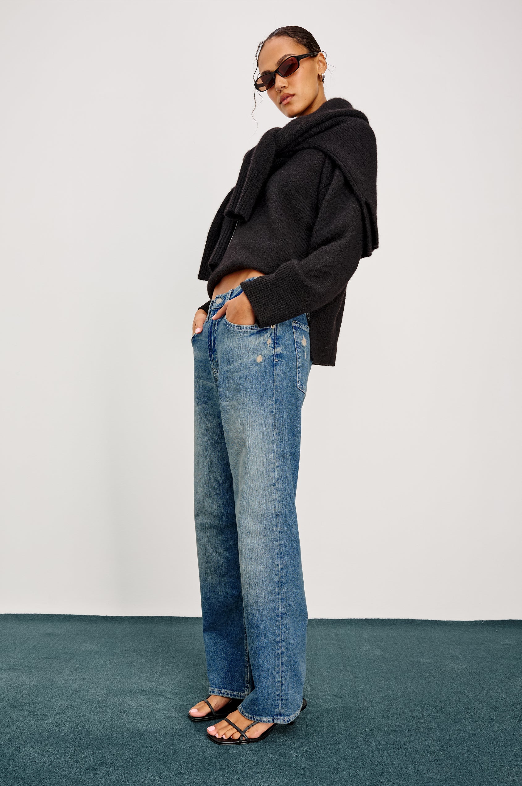 Del Mar low slung baggy boyfriend 5-pocket jean in medium wash Tinted Indigo Destroy, with light destruction near front pockets - full body side view with hands in front pockets featured on model.