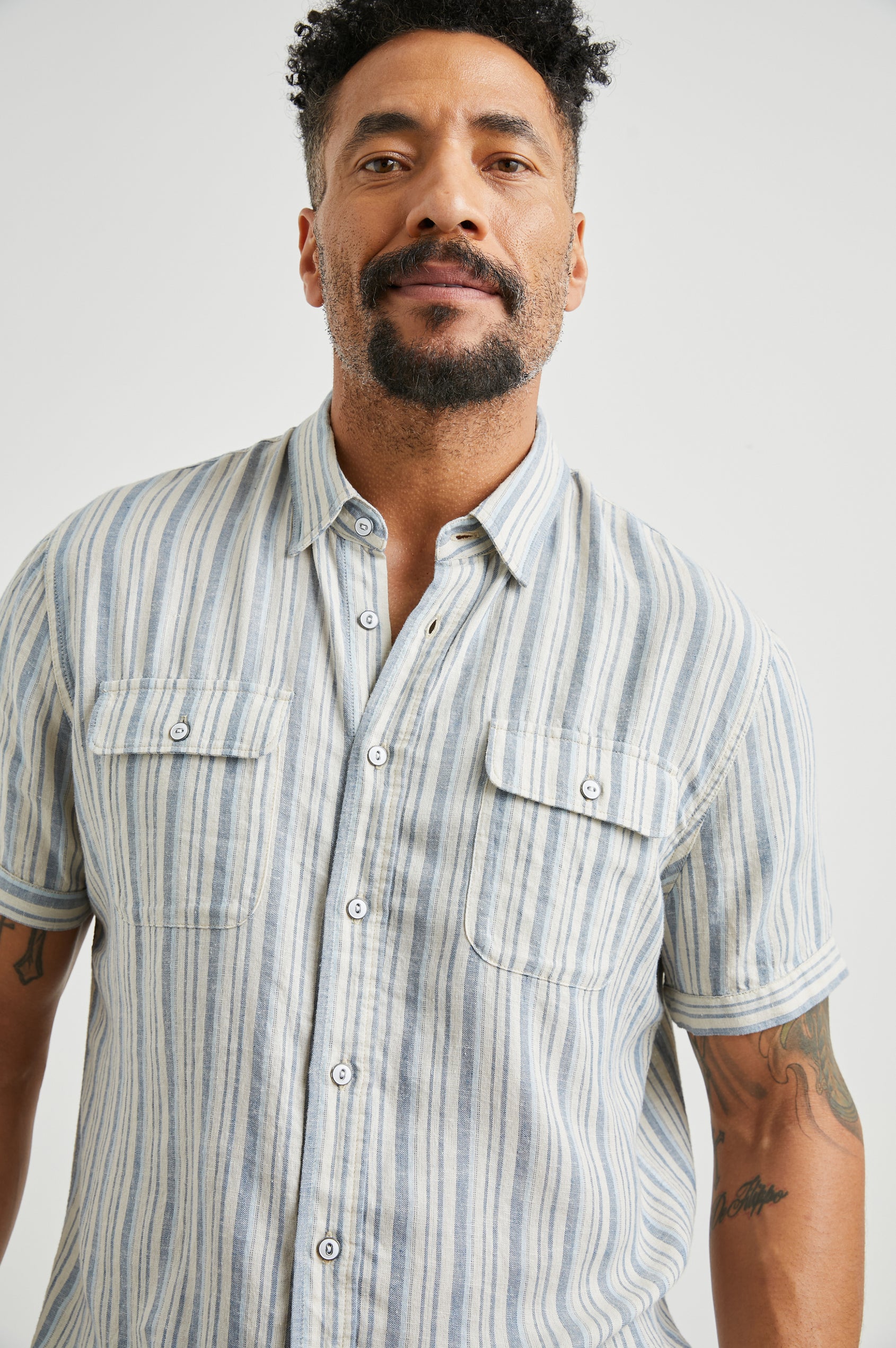 Donnie Short-Sleeve Button Up with Two Chest Button Flap Pockets in Blue Cap Range Colorway, Vertical Stripes in Muted Blues and Cream - Front View Featured on Model