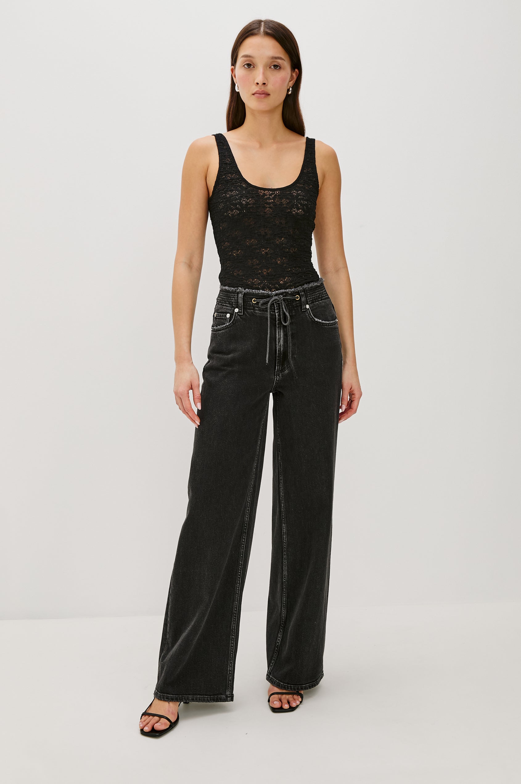 Donya is a sheer, unlined tank top with a scoop neckline in lace fabrication for added texture in Black Lace Colorway - Full Body Front View Featured on Model