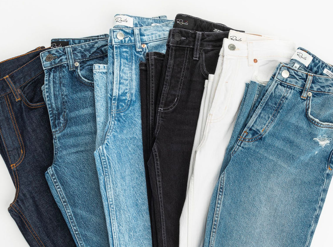 MULTIPLE PAIRS OF JEANS FOLDED AND PLACED NEXT TO EACH OTHER