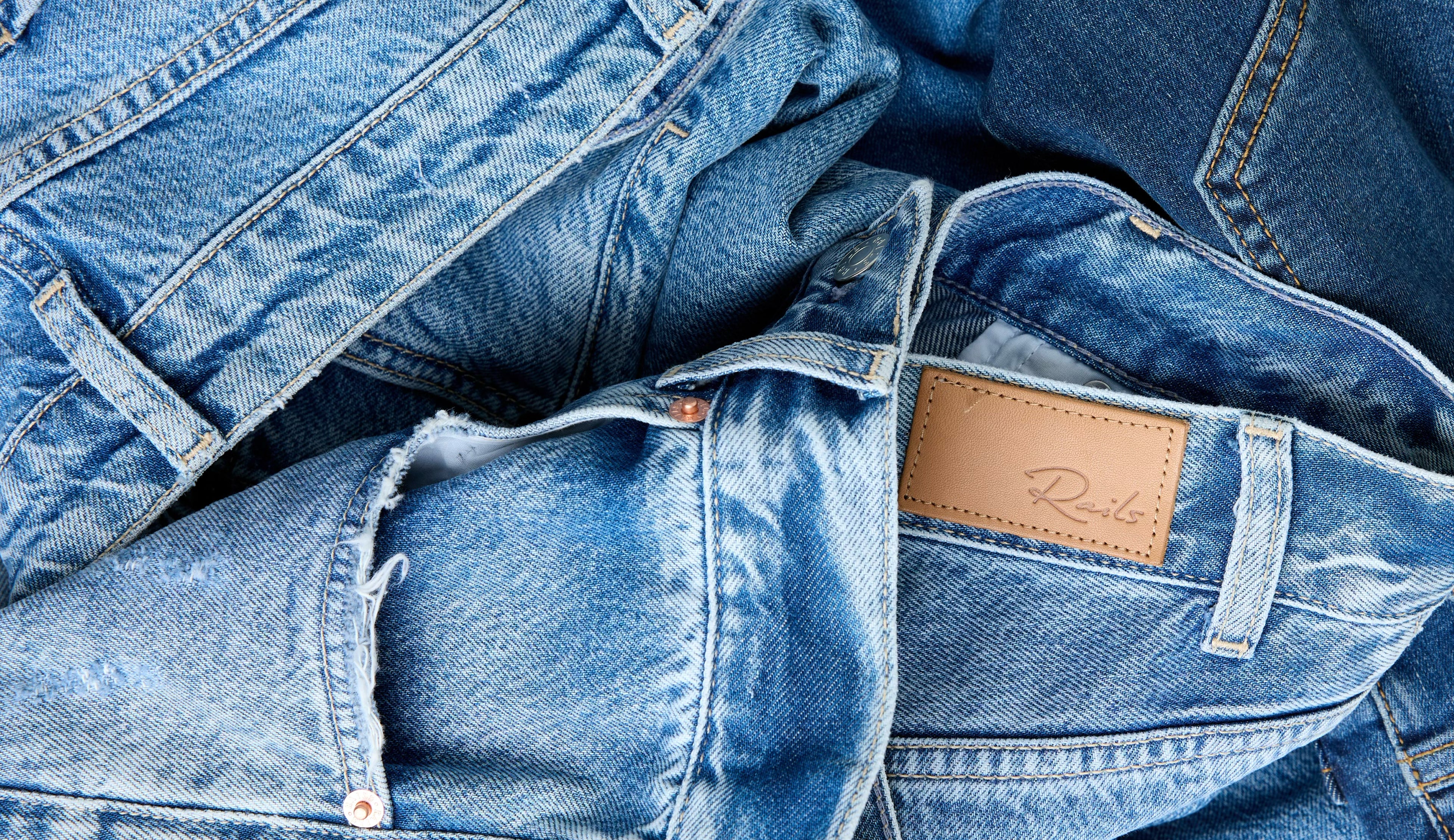 Stack of blue jeans with a brand label on a blue background
