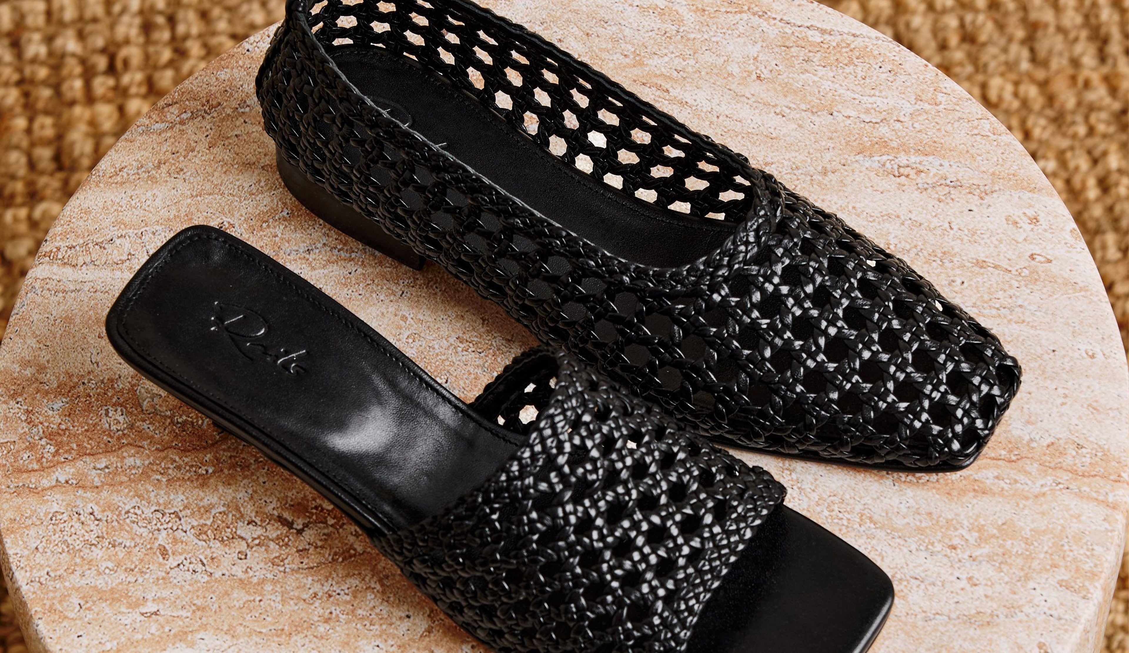 Image of two black woven shoes on a marble surface