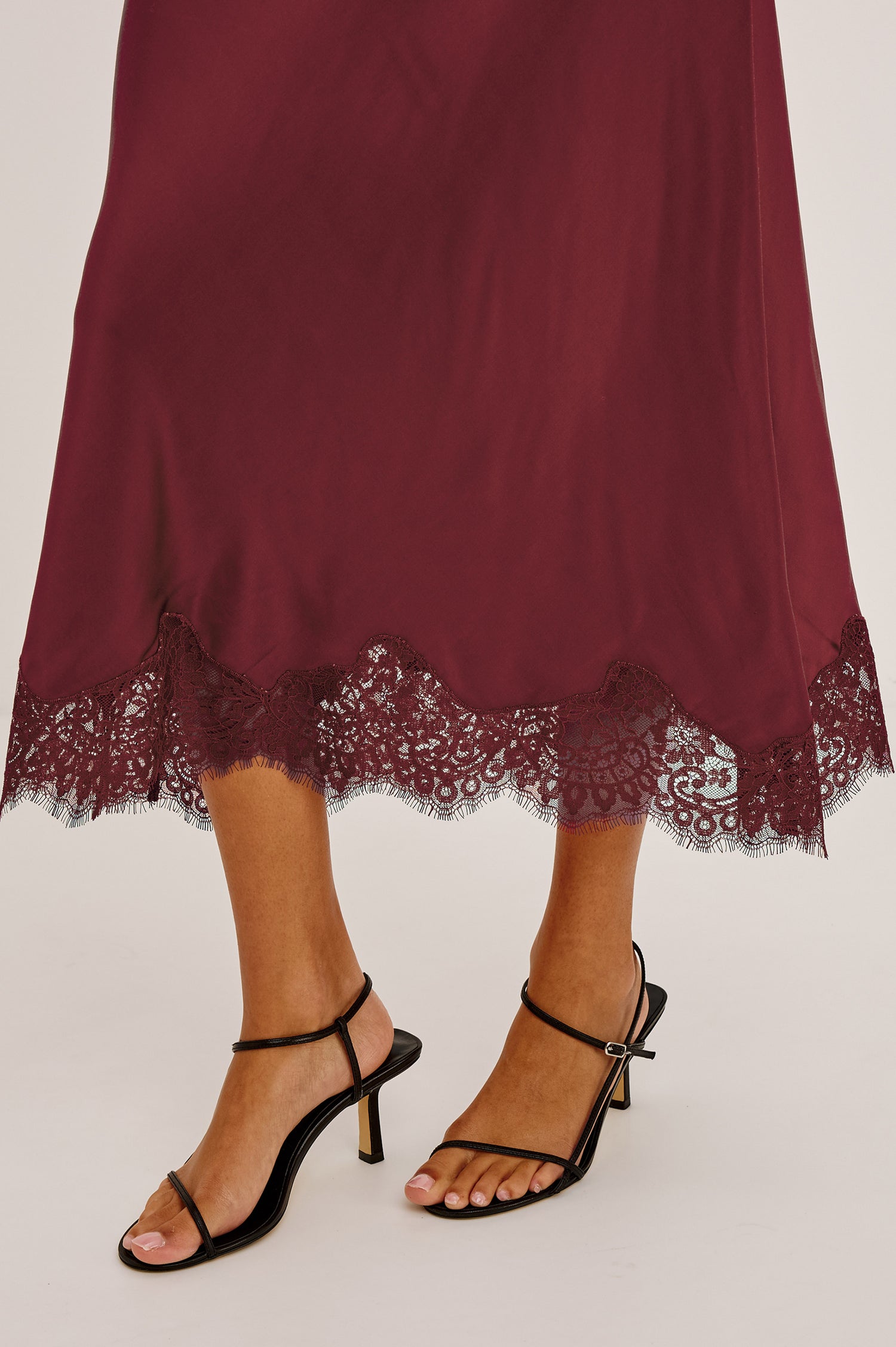 Ebony Midi Skirt Bias Cut in Satin With Clean Elastic Waistband, Pull-On Fit, and Tonal Lace Trim at Hem in Crimson Colorway - Lower Body Front View Featured on Model