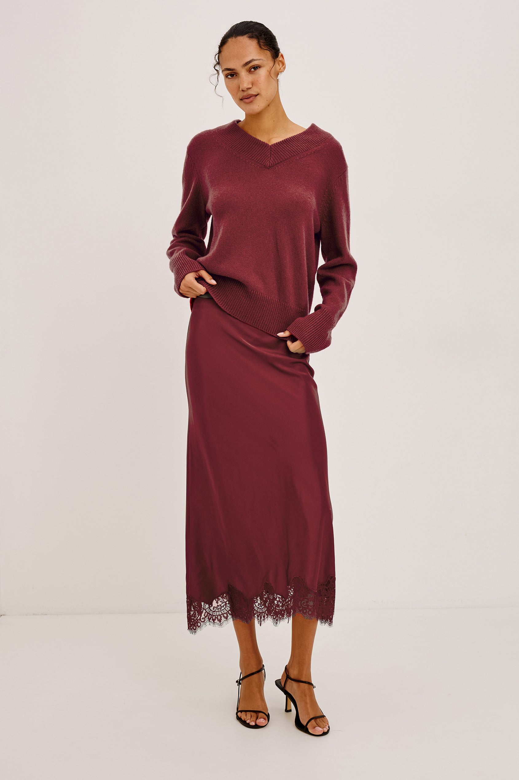 Ebony Midi Skirt Bias Cut in Satin With Clean Elastic Waistband, Pull-On Fit, and Tonal Lace Trim at Hem in Crimson Colorway - Full Body Front View Featured on Model