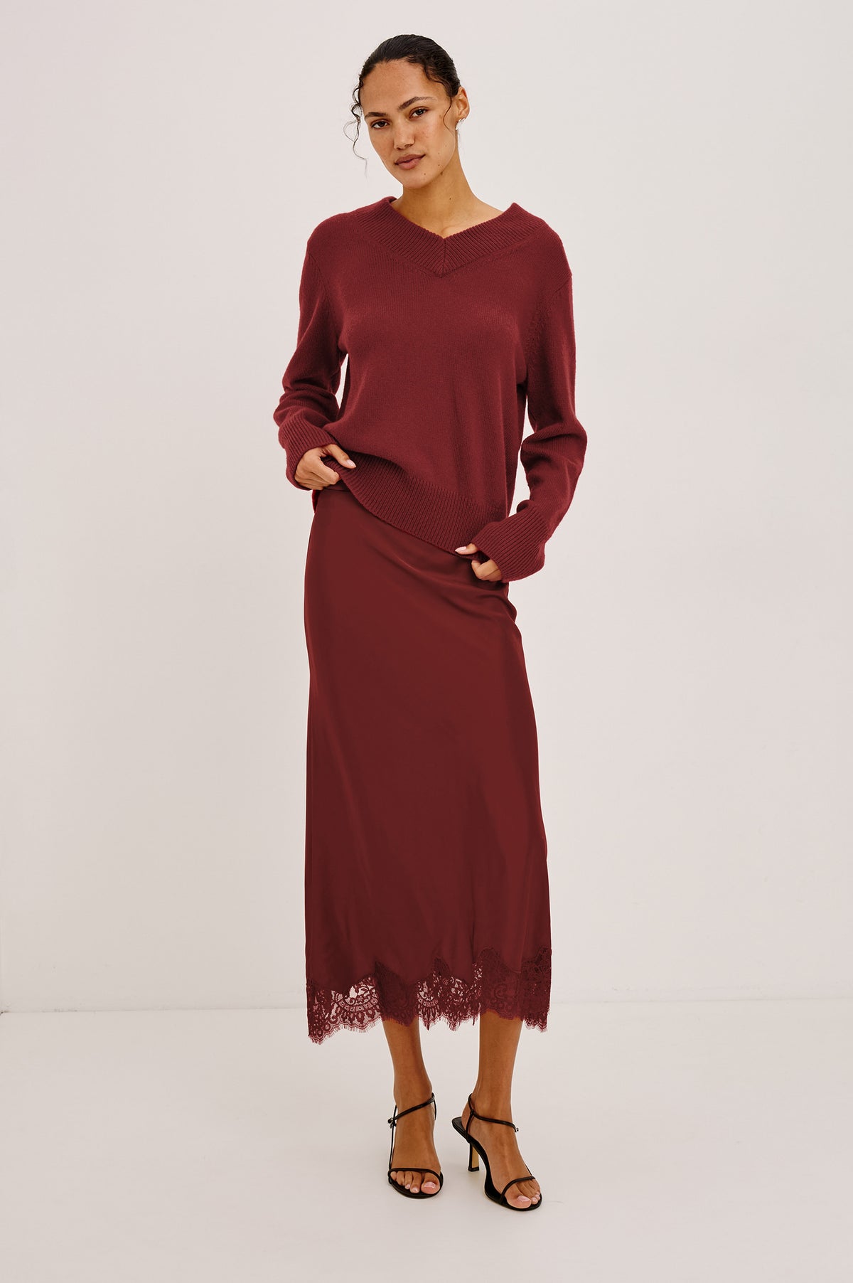 Ebony Midi Skirt Bias Cut in Satin With Clean Elastic Waistband, Pull-On Fit, and Tonal Lace Trim at Hem in Crimson Colorway - Full Body Front View Featured on Model