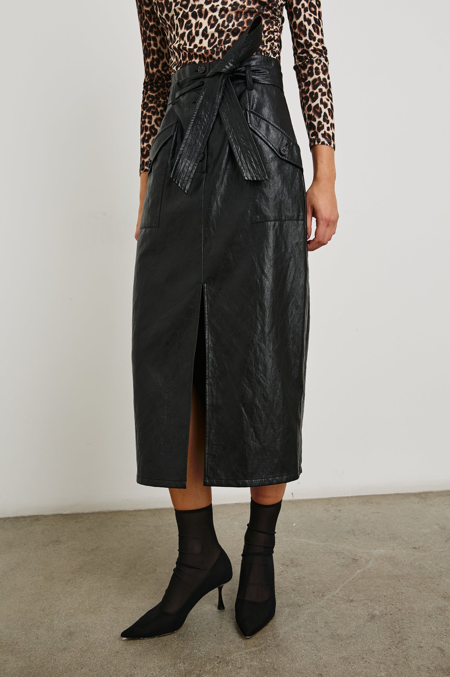 Edem Midi Skirt with a Tie Belt, a Center Slit, Four Button Closure at the Waist, Two Front Pockets Each Overlaid with a Button Flap Pocket and Two Back Welt Pockets in Black Colorway - Front View Featured on Model