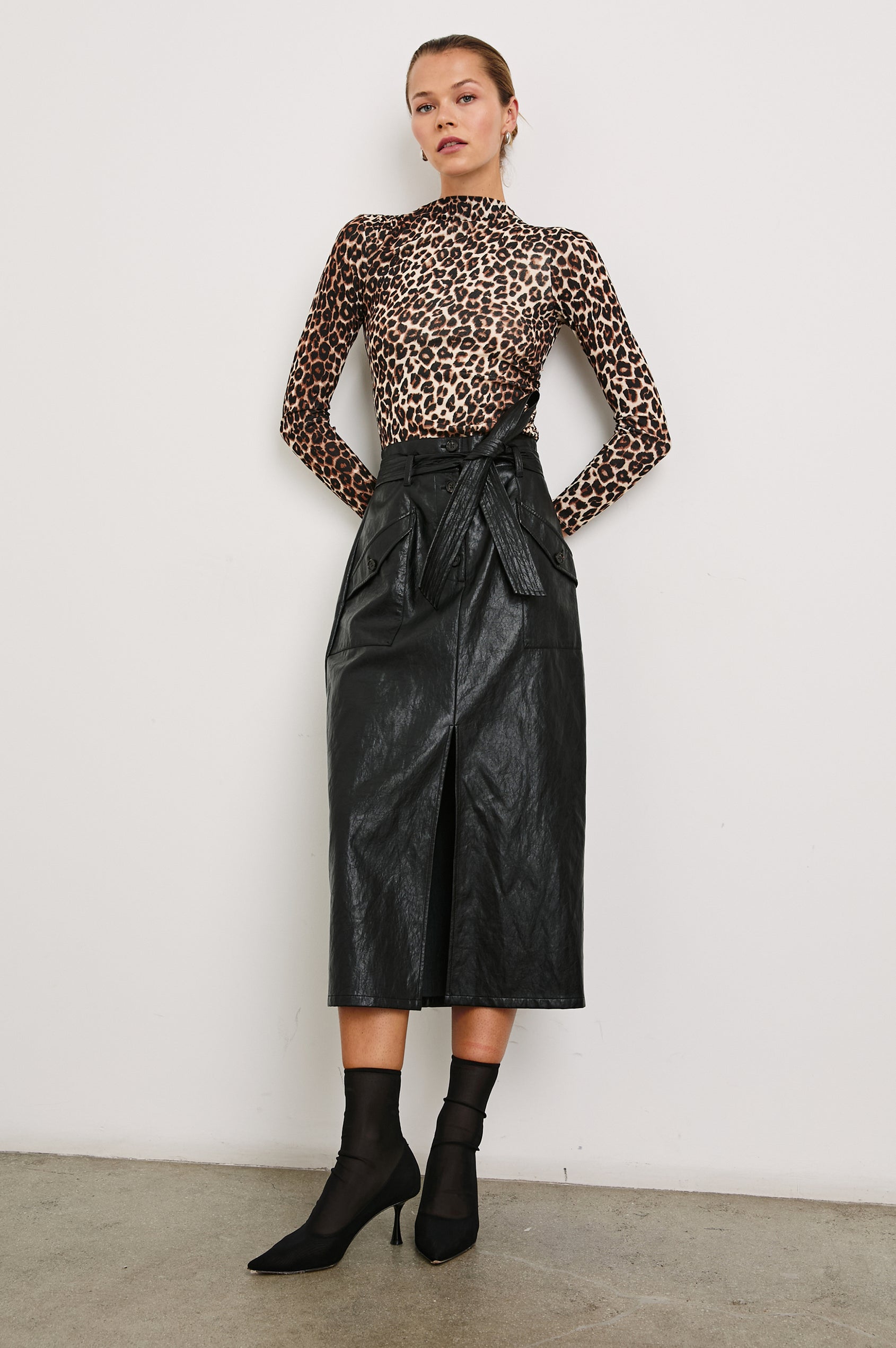 Edem Midi Skirt with a Tie Belt, a Center Slit, Four Button Closure at the Waist, Two Front Pockets Each Overlaid with a Button Flap Pocket and Two Back Welt Pockets in Black Colorway - Front Full Body View Featured on Model