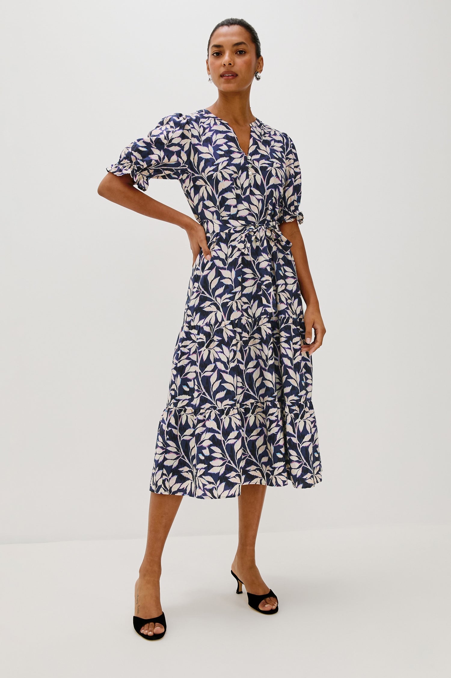Eliana Midi Dress with Elbow Length Sleeves with Elasticated Ruffle Hem, V-Neck, 3-Button Front, Self Waist Tie and Tiered Skirt in Navy Vines Colorway. Front Full Body View Featured on Model.