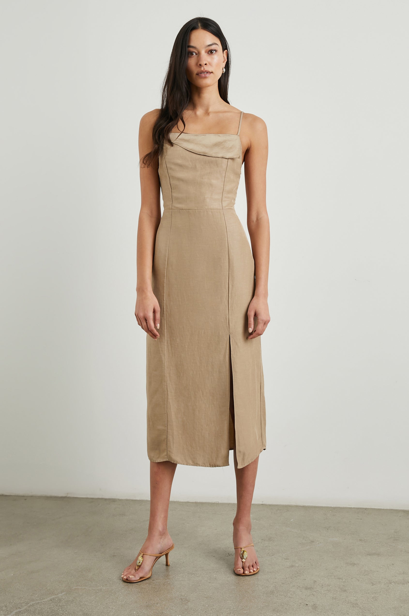 Ellasandra Sleeveless Midi Dress with Adjustable Spaghetti Straps, a Square Neckline, an Asymmetric Folded Flap at the Neckline, and a Front Thigh Slit in Safari Colorway, a Tan - Front Full Body View Featured on Model  