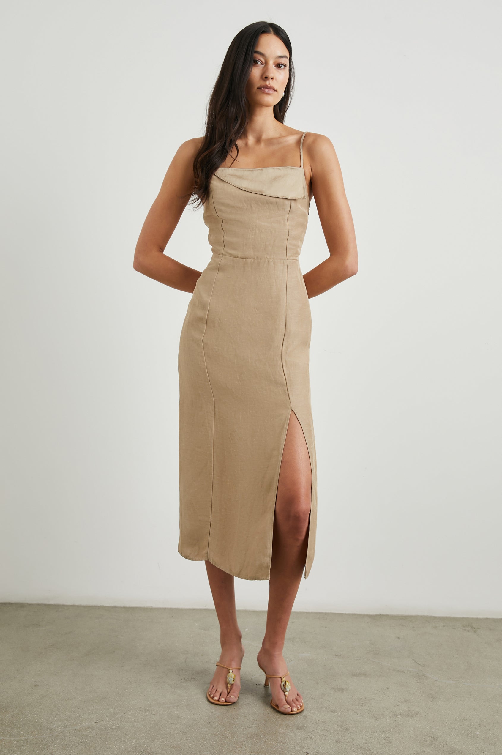 Ellasandra Sleeveless Midi Dress with Adjustable Spaghetti Straps, a Square Neckline, an Asymmetric Folded Flap at the Neckline, and a Front Thigh Slit in Safari Colorway, a Tan - Front Full Body View Featured on Model  