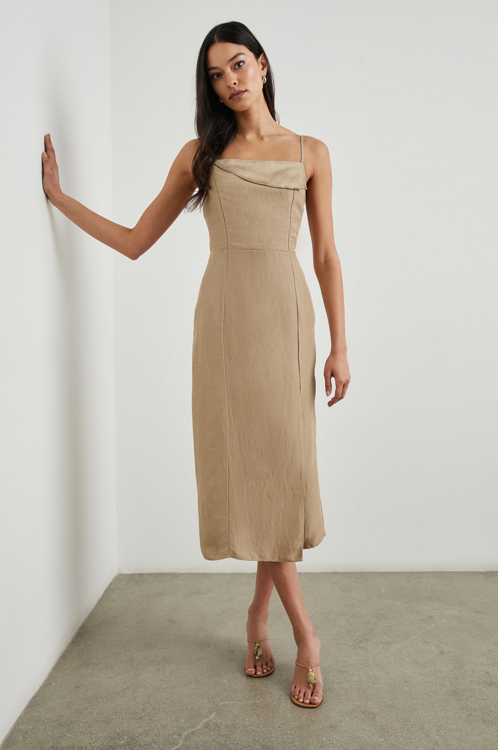 Ellasandra Sleeveless Midi Dress with Adjustable Spaghetti Straps, a Square Neckline, an Asymmetric Folded Flap at the Neckline, and a Front Thigh Slit in Safari Colorway, a Tan - Front Full Body View Featured on Model  