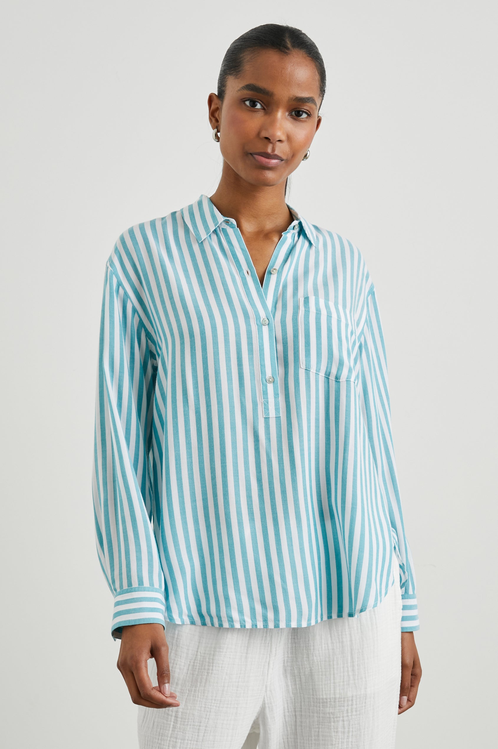 Elle Long Sleeve Shirt with a Four Button Placket, Buttoned Cuffs, a Chest Pocket and a Collar in Saltan Stripe Colorway, White and Blue Vertical Stripes - Front View Featured on Model
