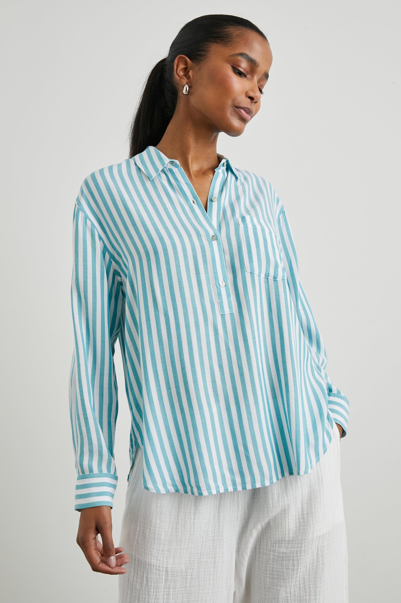 Elle Long Sleeve Shirt with a Four Button Placket, Buttoned Cuffs, a Chest Pocket and a Collar in Saltan Stripe Colorway, White and Blue Vertical Stripes - Front View Featured on Model