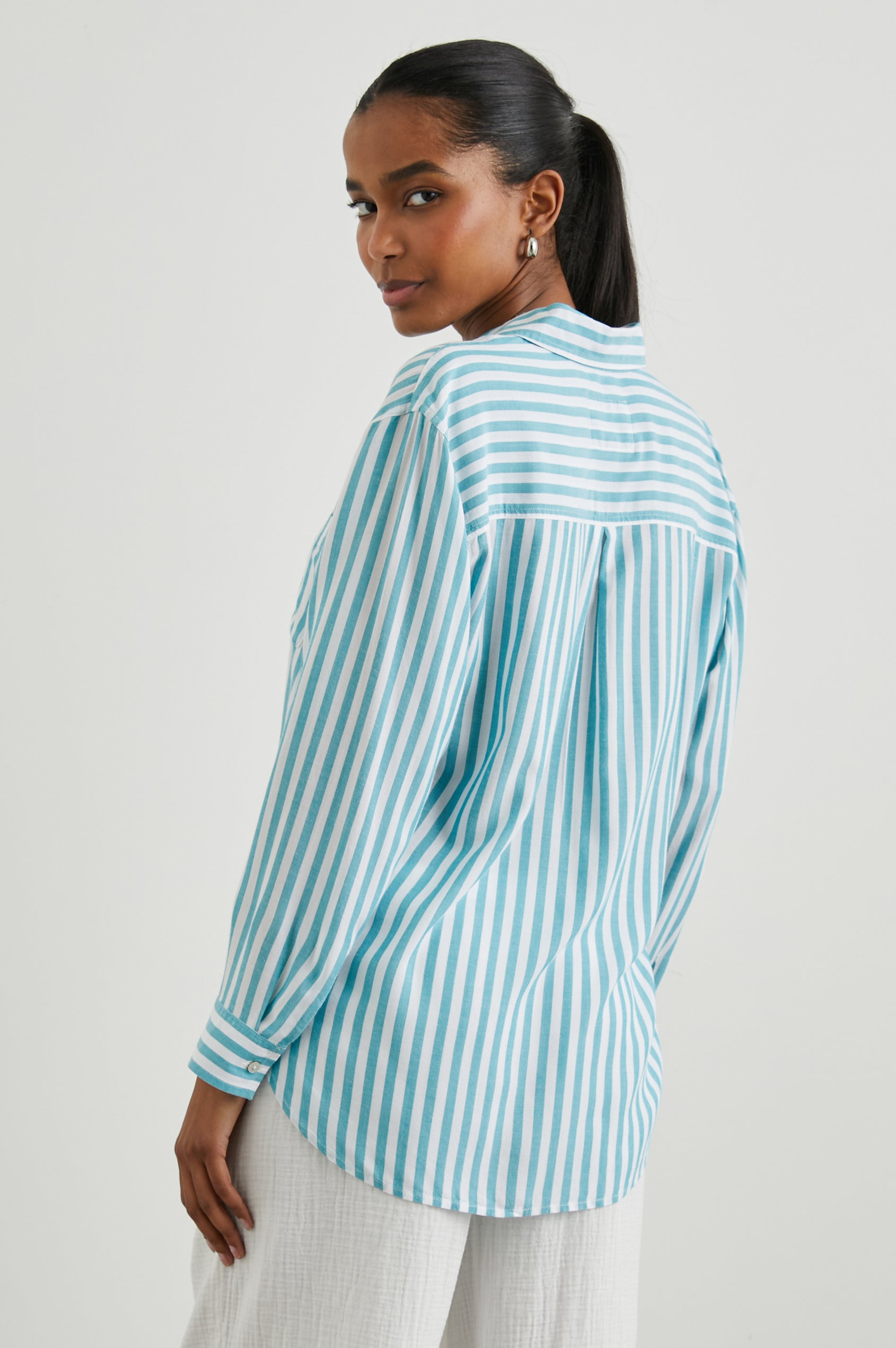 Elle Long Sleeve Shirt with a Four Button Placket, Buttoned Cuffs, a Chest Pocket and a Collar in Saltan Stripe Colorway, White and Blue Vertical Stripes - Back View Featured on Model