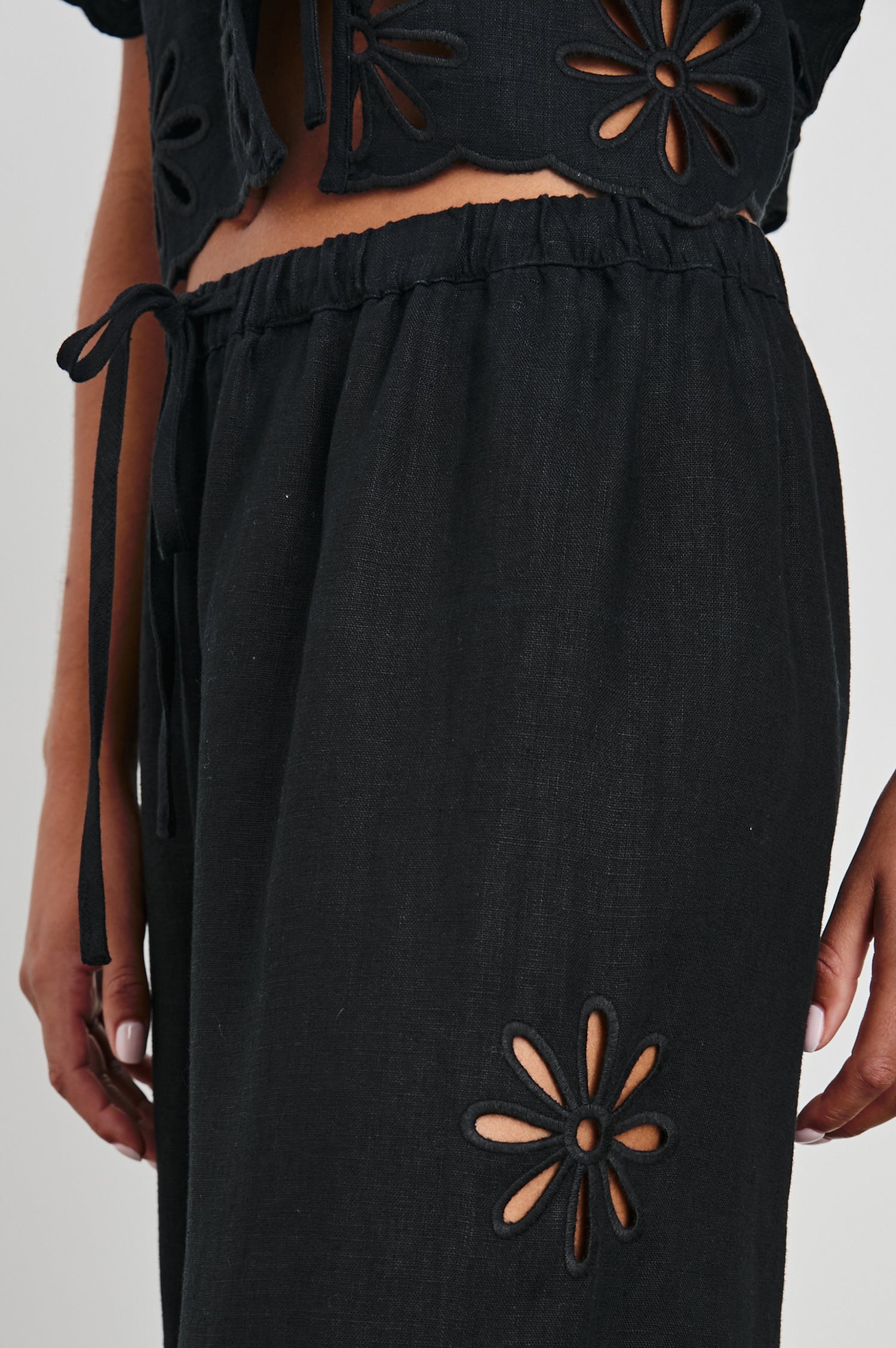 Emmie Pants with a Drawstring Waist and Two Front Pockets in Black Eyelet Colorway, with eyelets along the outer and inner sides  - Front View Featured on Model