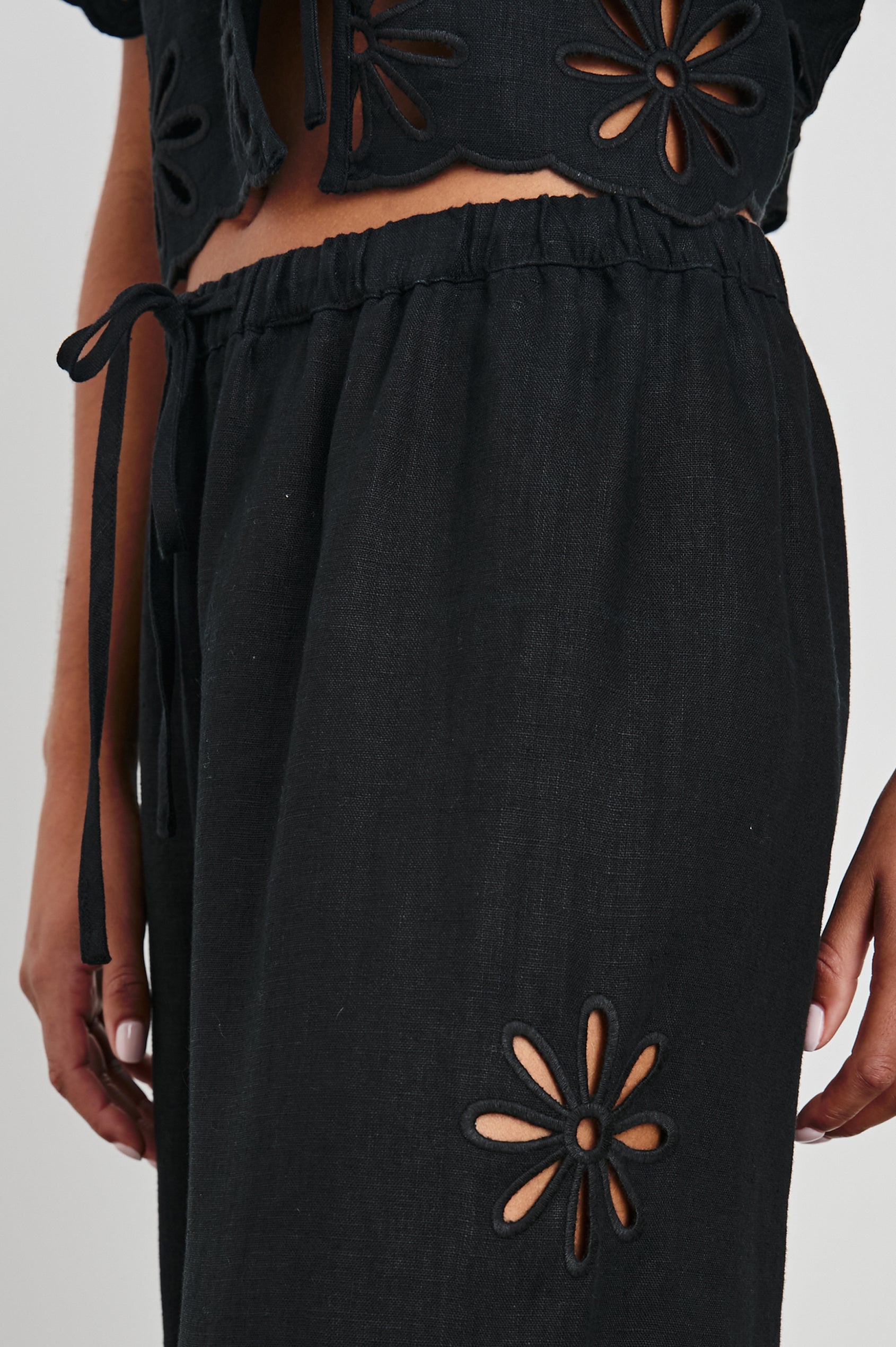 Emmie Pants with a Drawstring Waist and Two Front Pockets in Black Eyelet Colorway, with eyelets along the outer and inner sides  - Front View Featured on Model